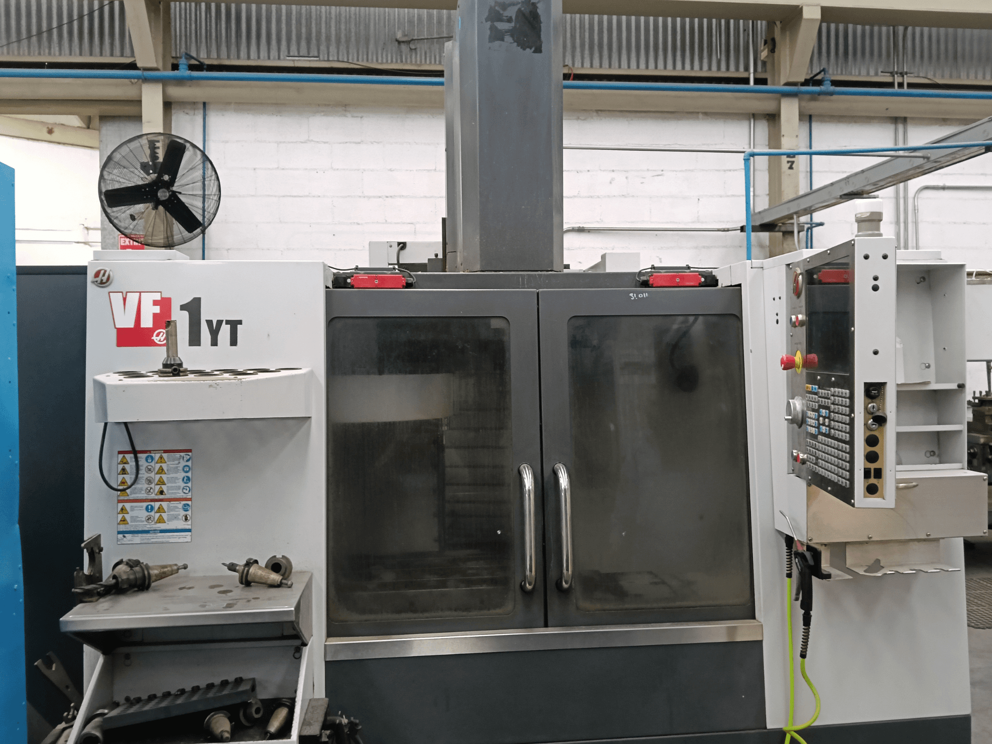 Front view of HAAS VF-1YT-1 vertical machining center with control panel and tools on the side.