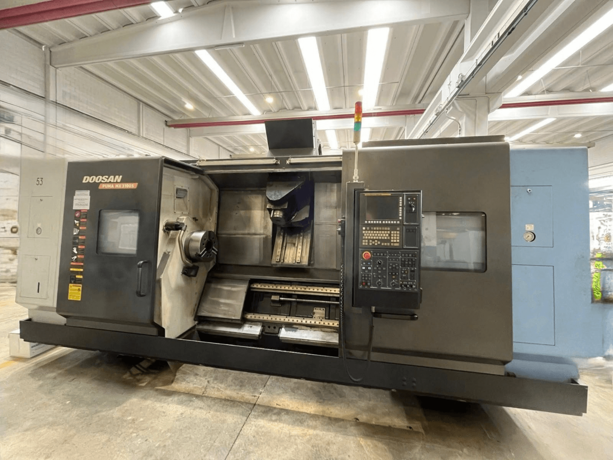 Front view of a DOOSAN PUMA MX3100 horizontal turning machine with a control panel and visible spindle and tool holder area.