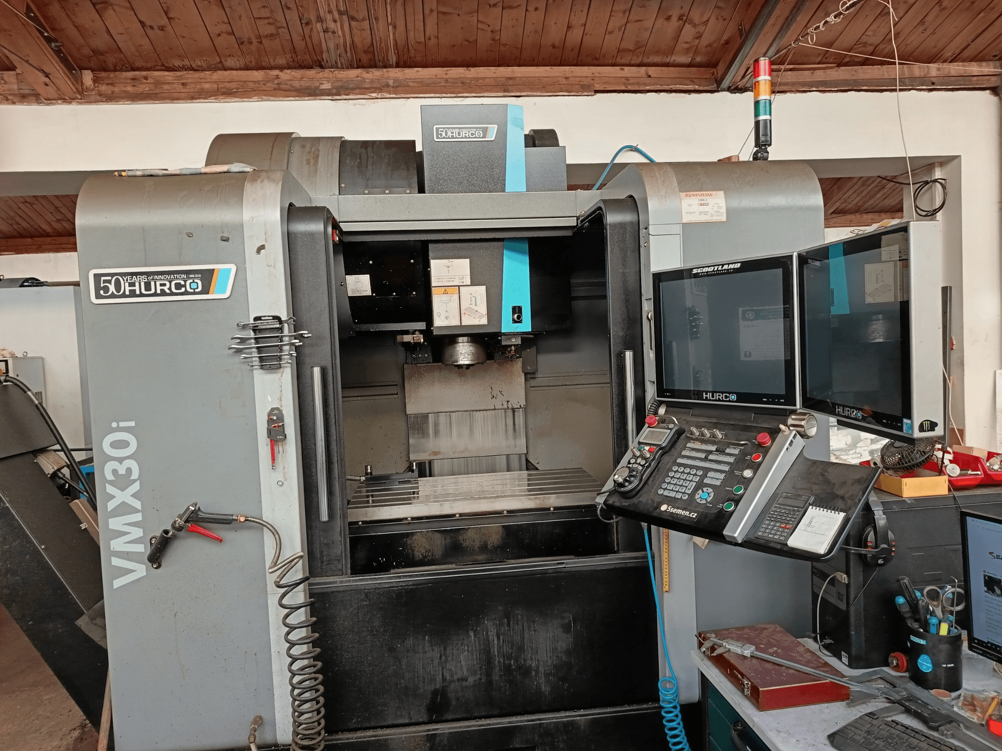 Hurco VMX30i CNC milling machine in front view, featuring dual monitors, control panel, and a hose attached.