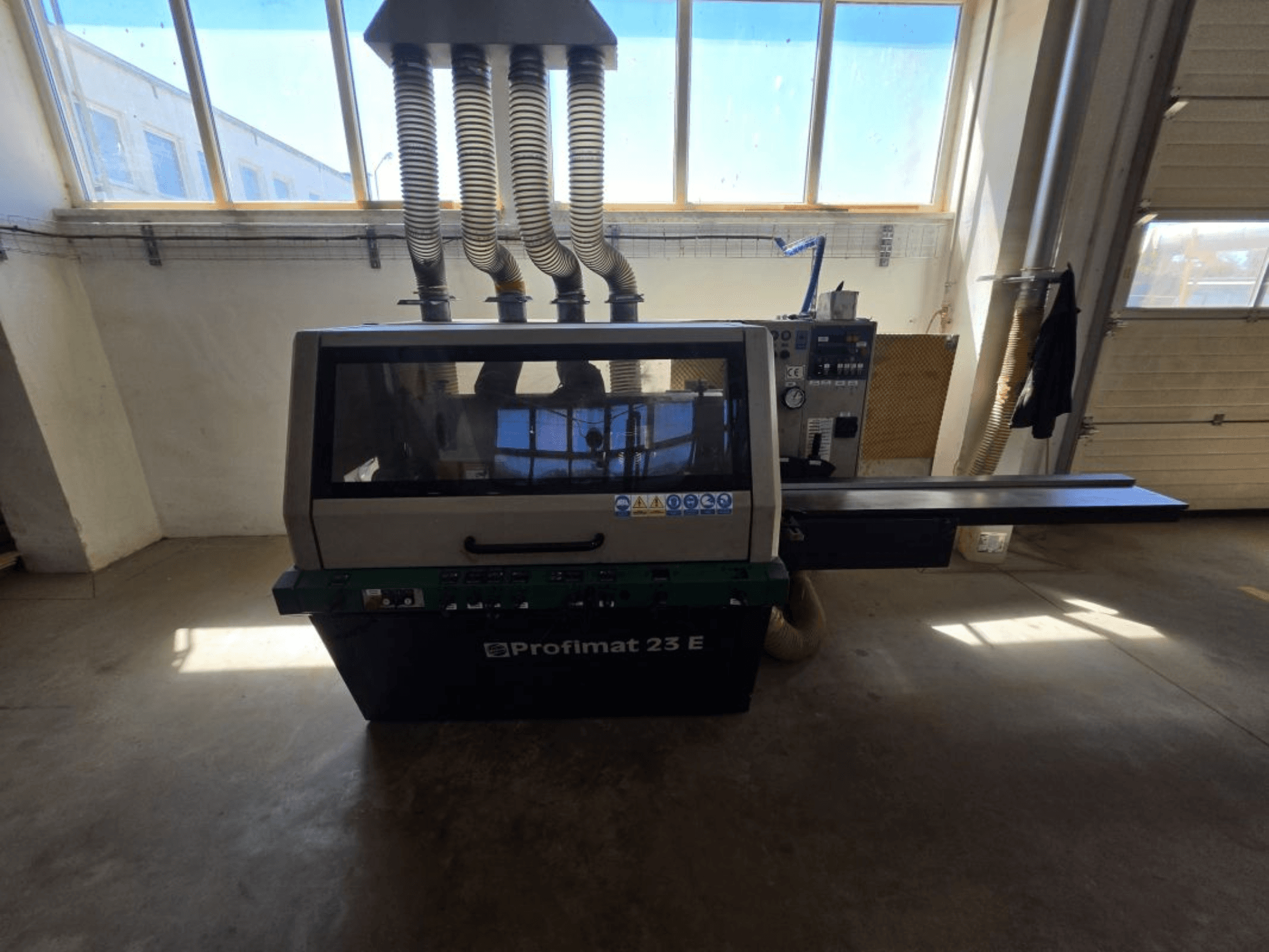 Wood planer WEINIG DIMTER PROFIMAT 23 E, front view, with control panel and dust extraction hoses visible, in a workshop setting.