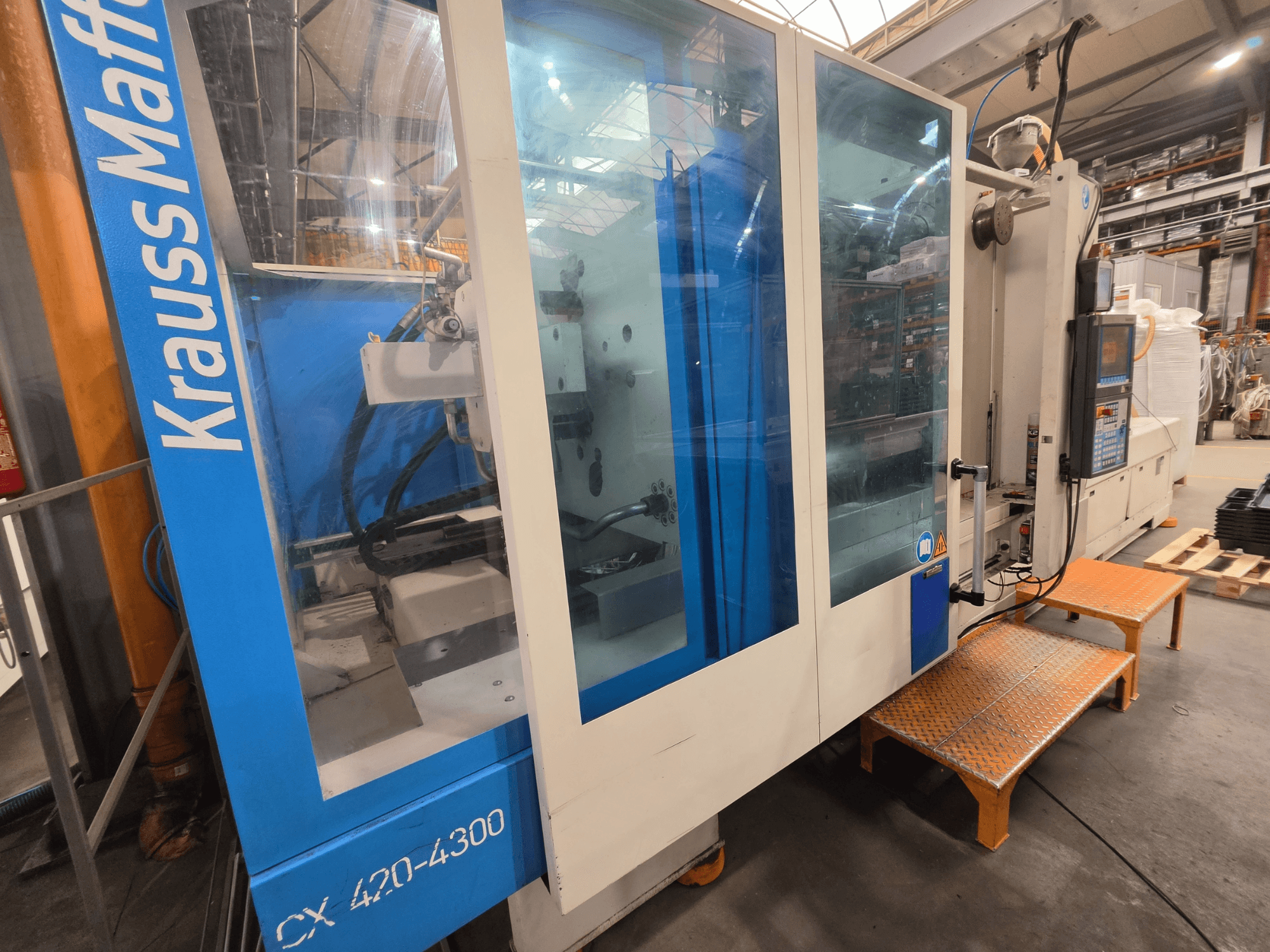 Krauss Maffei CX 420-4300 hydraulic injection moulding machine, side view, showing control panel and transparent panels.