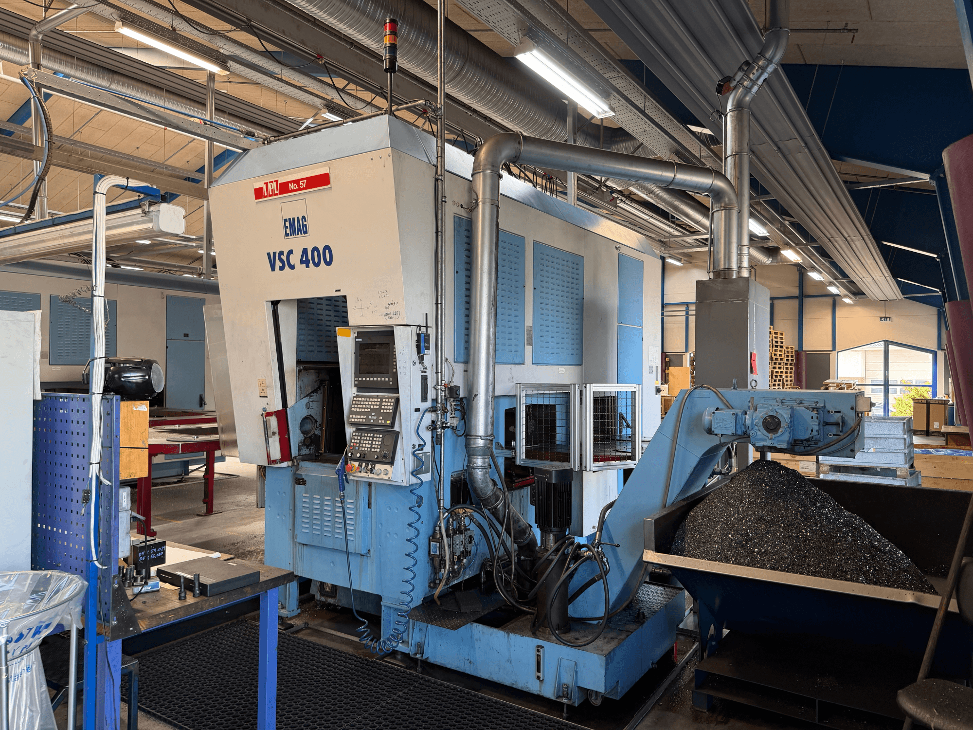 EMAG VSC 400 vertical turning machine, front view, showcasing control panel and swarf conveyor. Industrial setting visible.