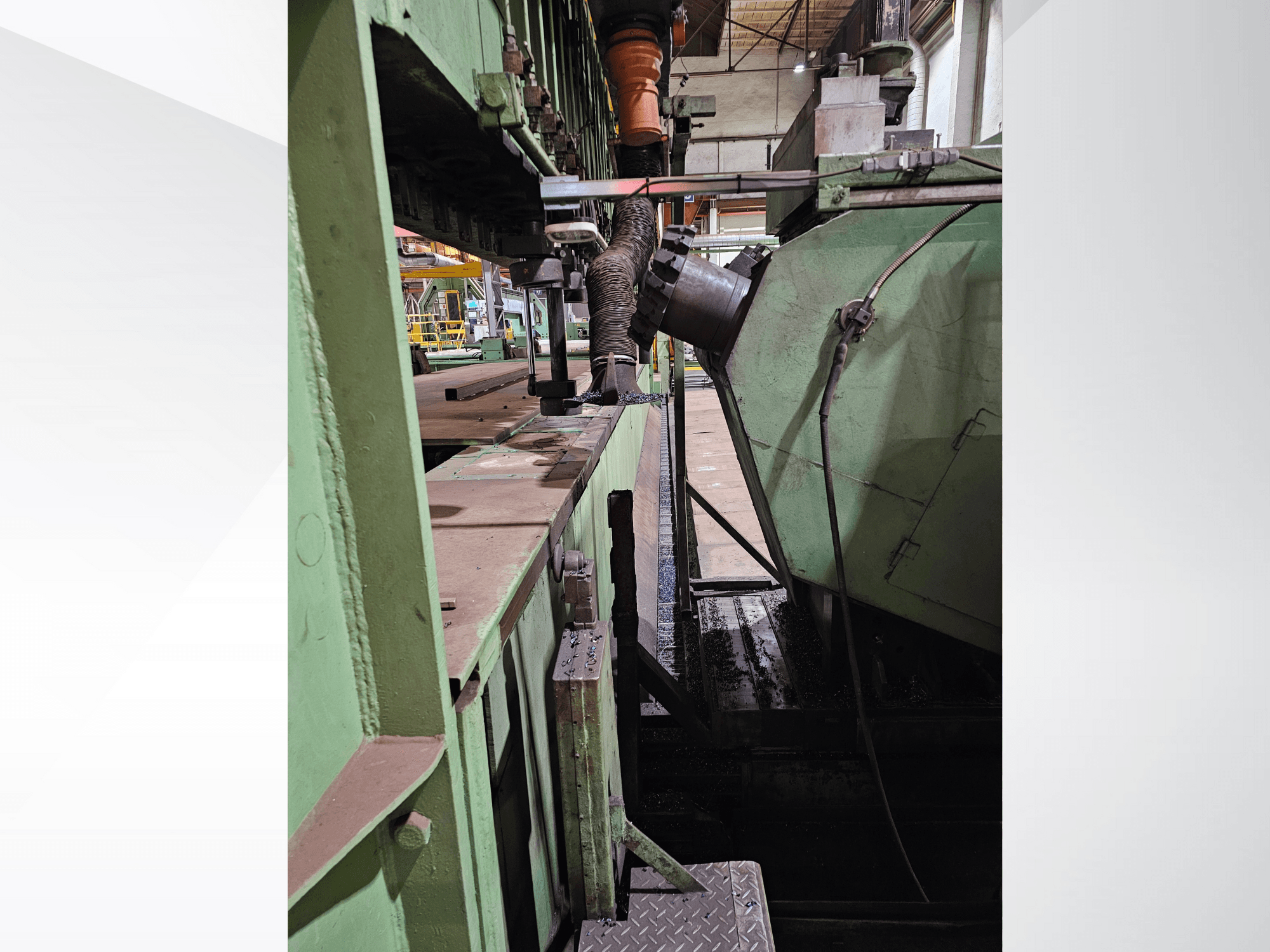 Green industrial machinery with a side view of a hopper and feeding mechanism, showcasing metal components and a platform.