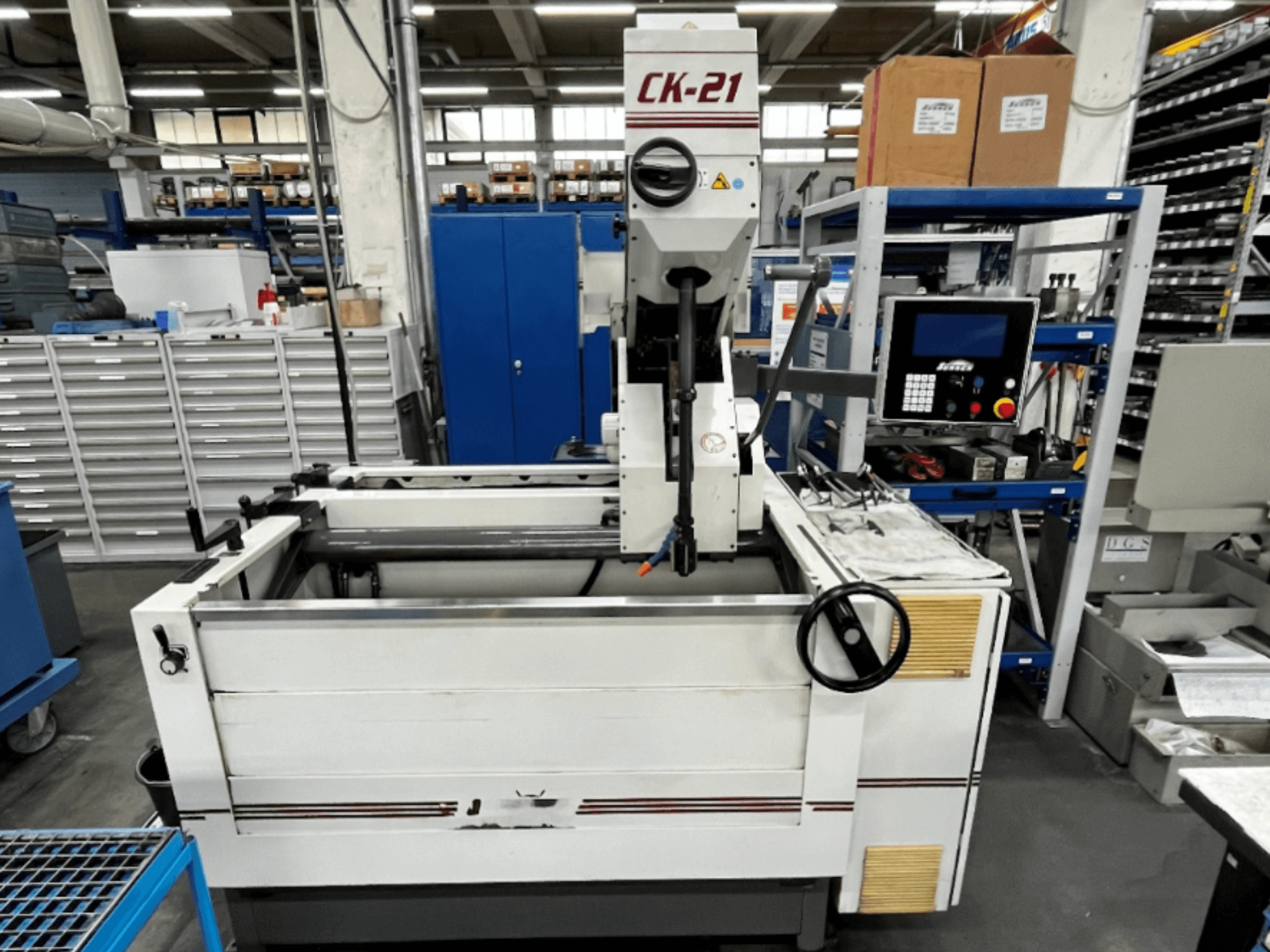 Sunnen CK-21-CC vertical honing machine in front view, featuring controls, honing area, and supporting equipment in background.