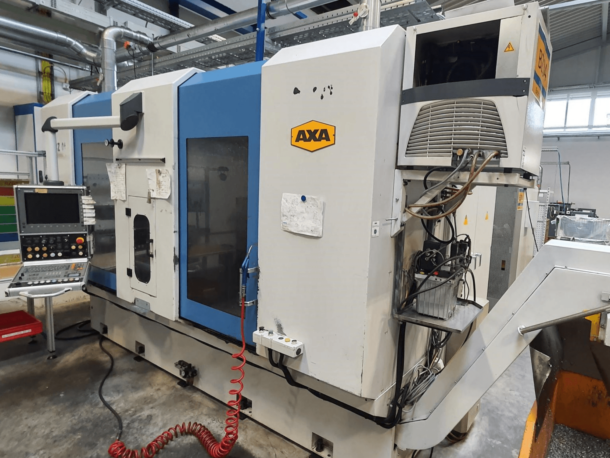 AXA DBZ vertical machining centre, front view, with control panel and visible coolant system detail.