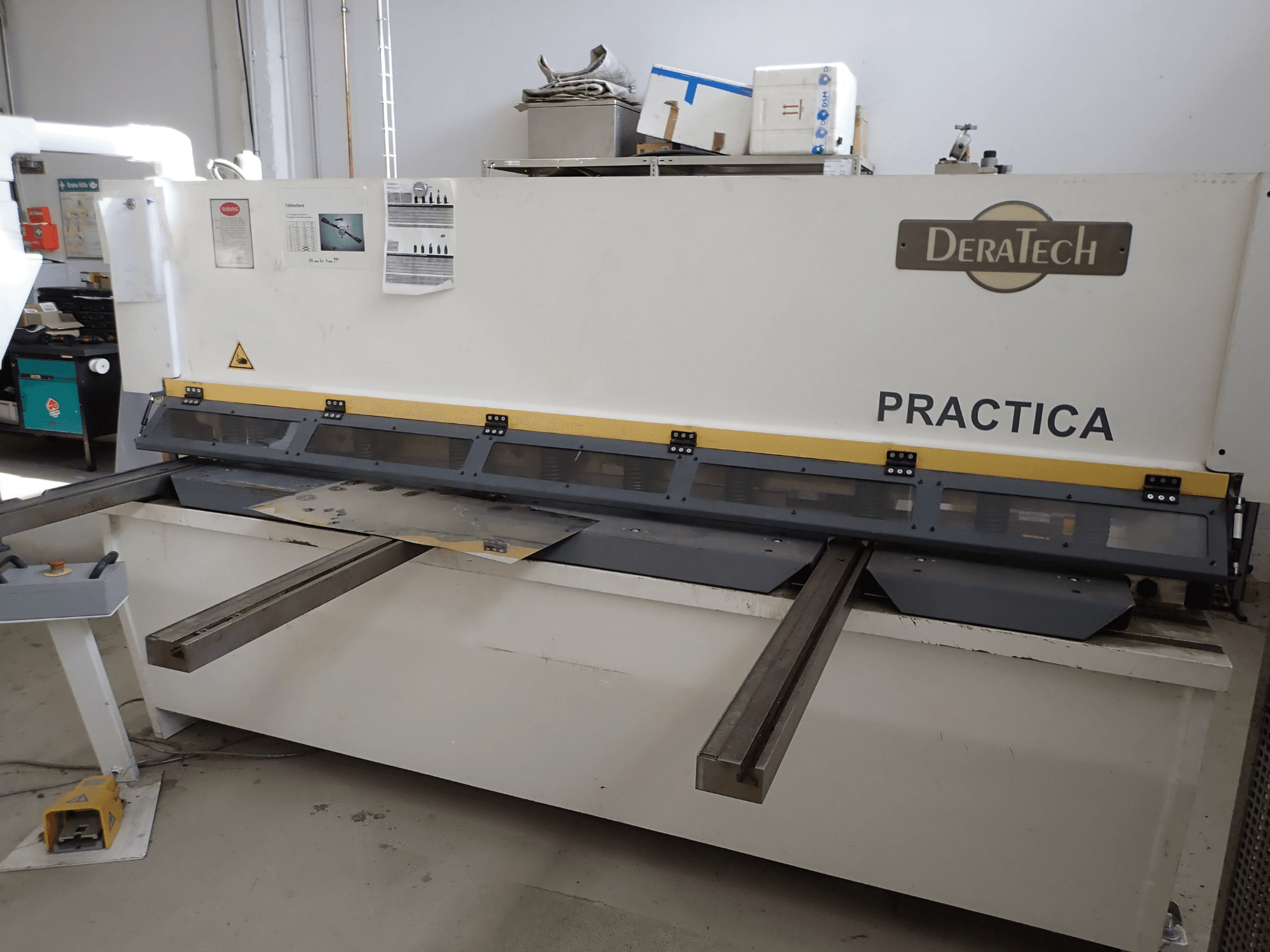 DERATECH Practica CNC shearing machine, front view, showing cutting blade and metal sheets on the work surface.