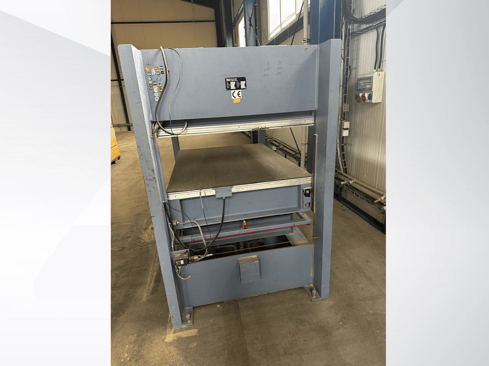 Gray industrial machine with control panel, viewed from the front; includes adjustable platforms and safety markings.