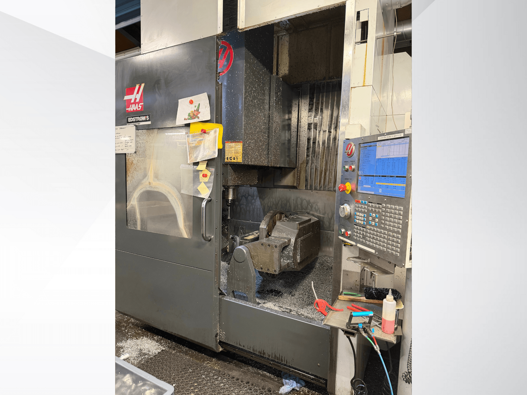 Haas CNC machine model EDSTROM S, front view, displaying metal workpiece, control panel, and metal shavings inside.