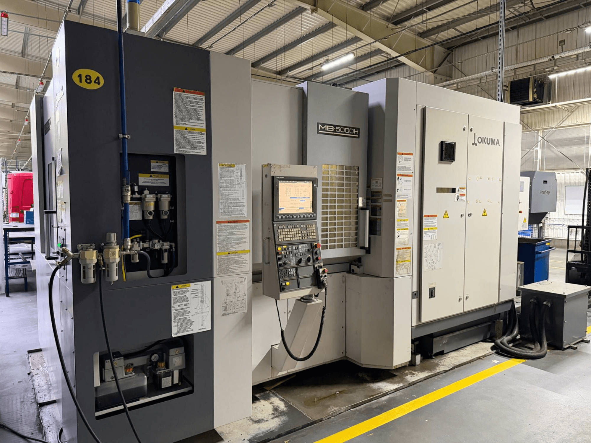 Okuma MB 5000H horizontal machining center front view, featuring controls, labeling, and hydraulic connections.