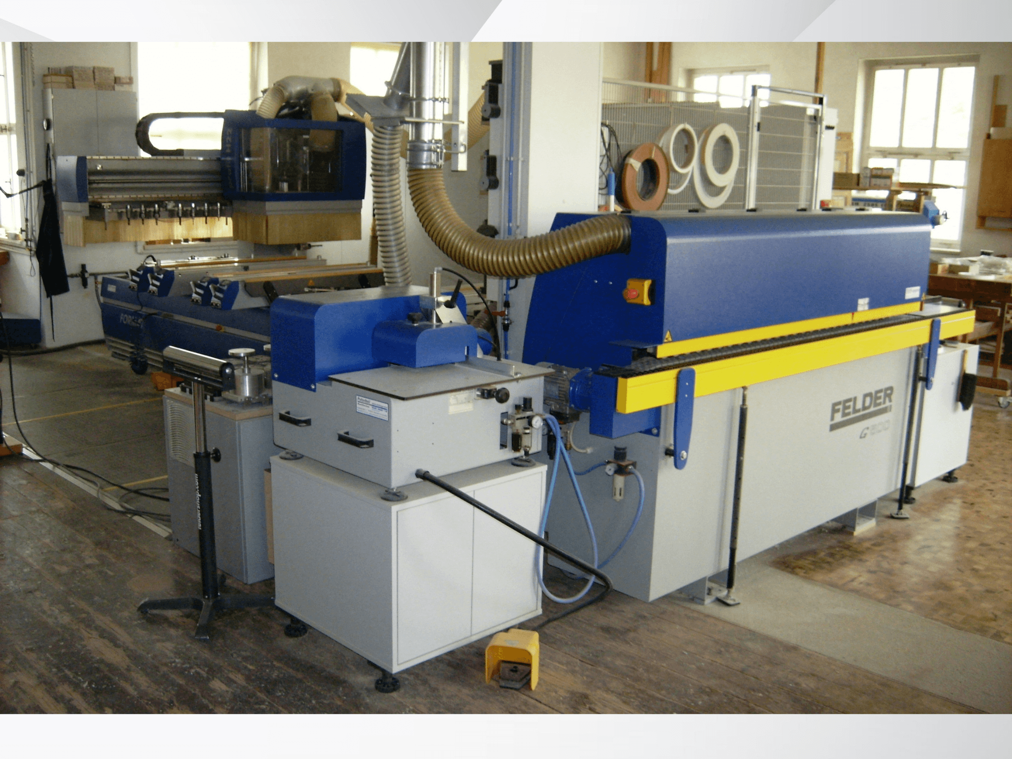 FELDER G500 edgebander in a workshop, side view showing the blue and yellow structure with controls and ducting.