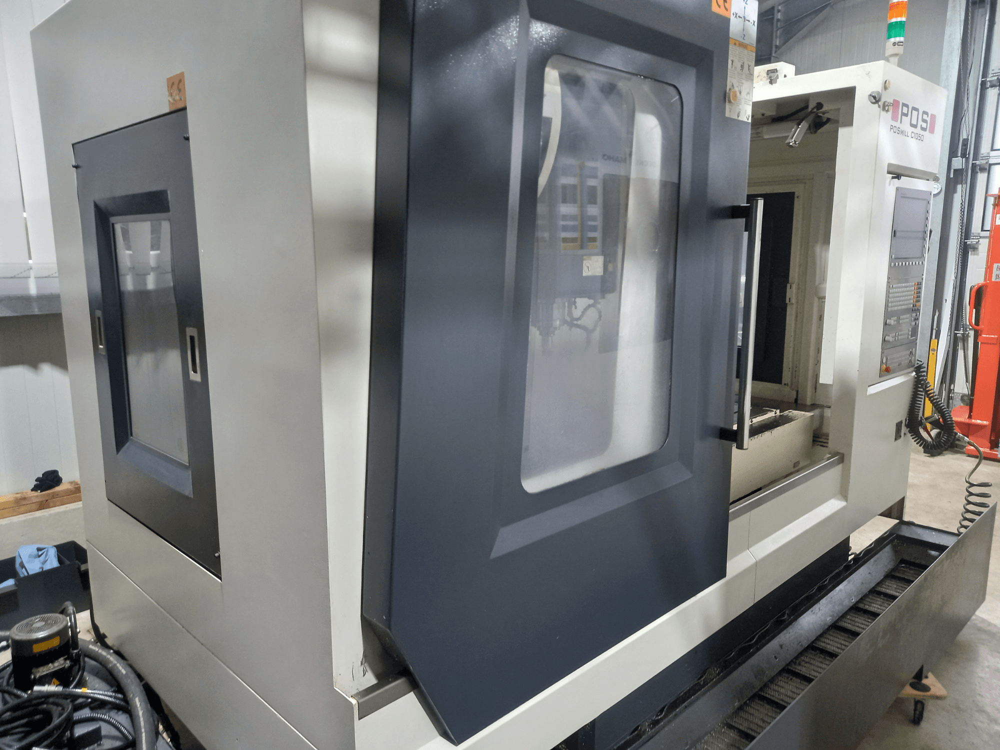 POSmill C 1050 vertical machining center, side view with open door, showing workspace and control panel details.