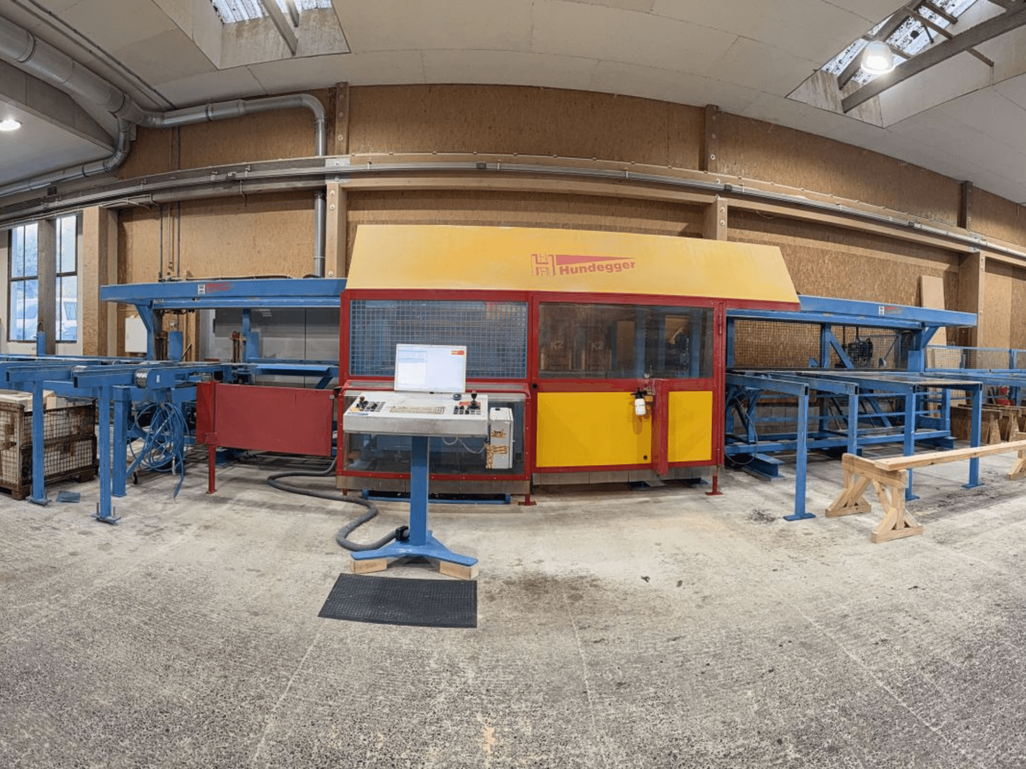 Front view of the HUNDEGGER K2-4-450 complete wood production line, featuring a control panel and conveyor system.