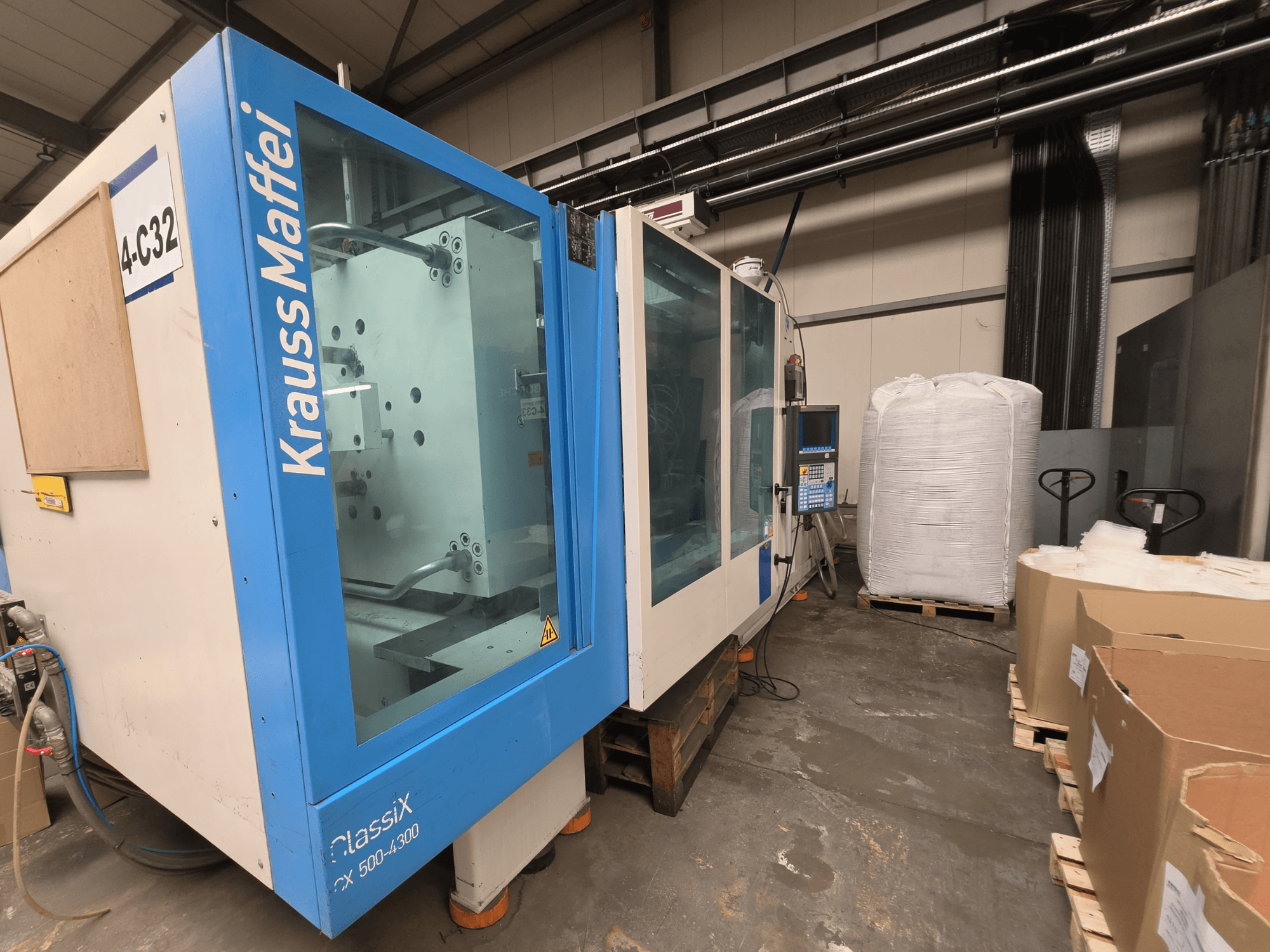 Krauss Maffei 500-4000 CX hydraulic injection moulding machine, side view, showcasing control panel and nearby packaging materials.