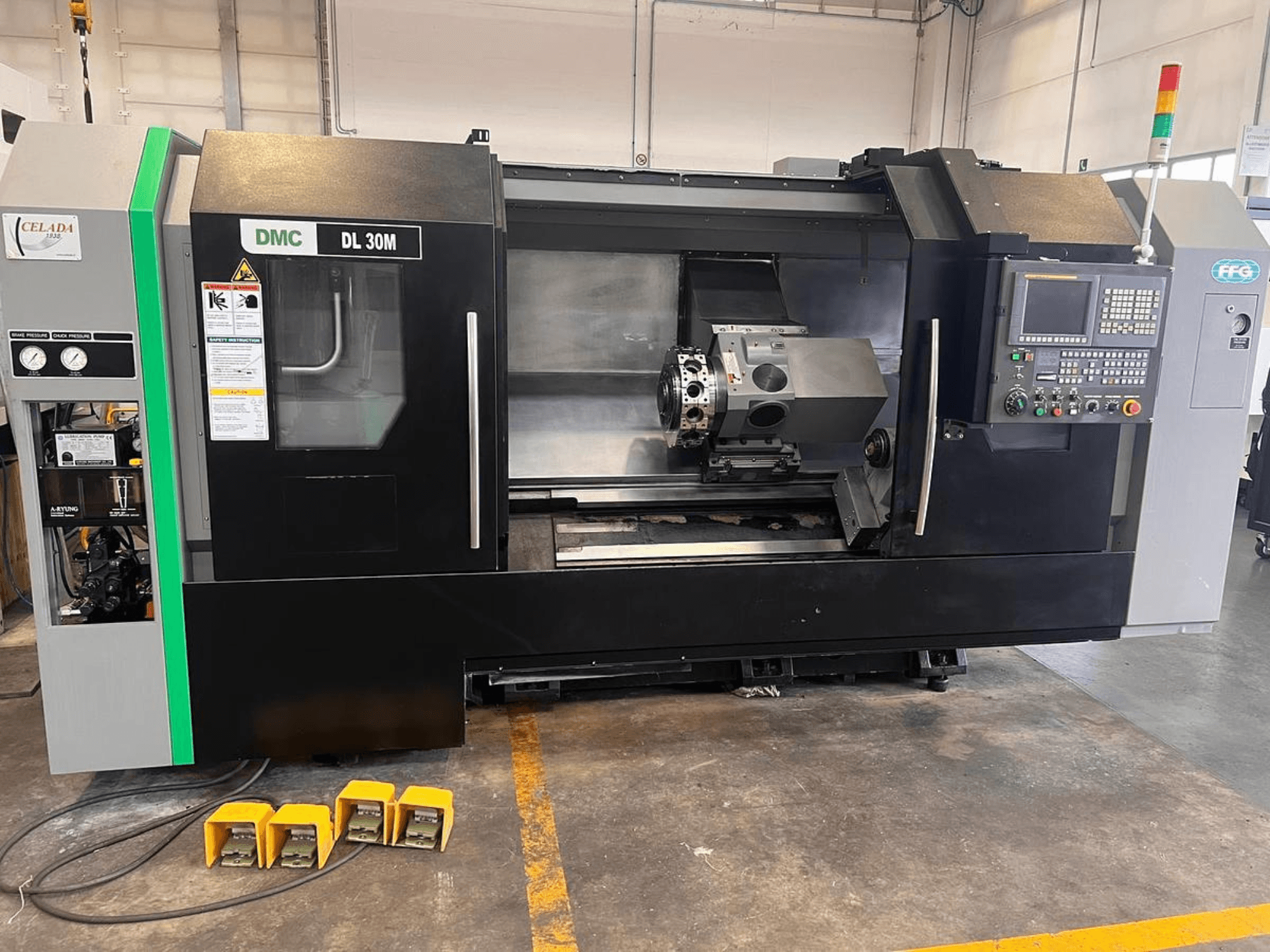 DMC DL 30M CNC machine with a side view showcasing controls, spindle, and three foot pedals on the floor.