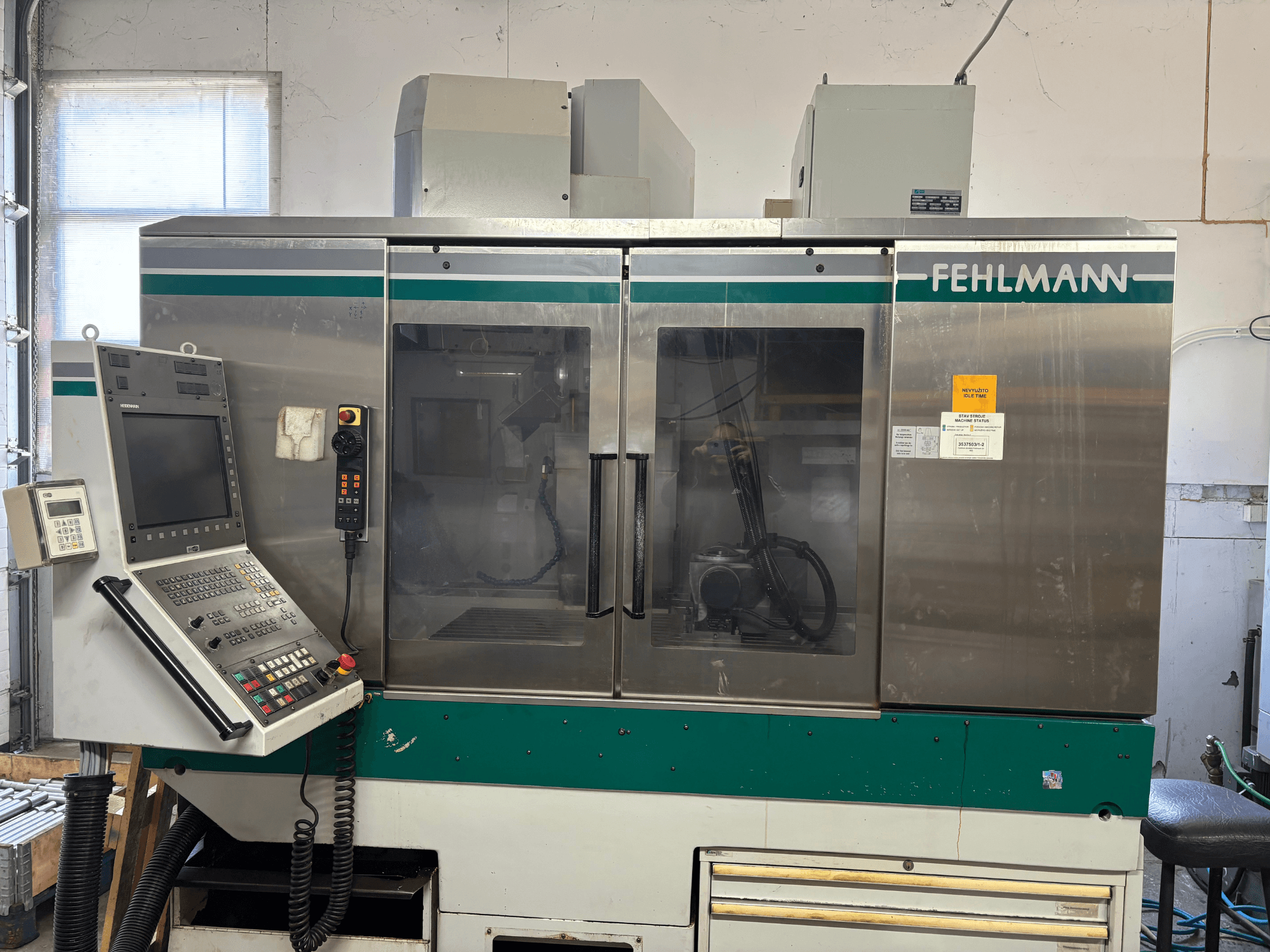 Front view of FEHLMANN Picomax 90-M vertical machining center, featuring control panel, clear casing, and operational buttons.