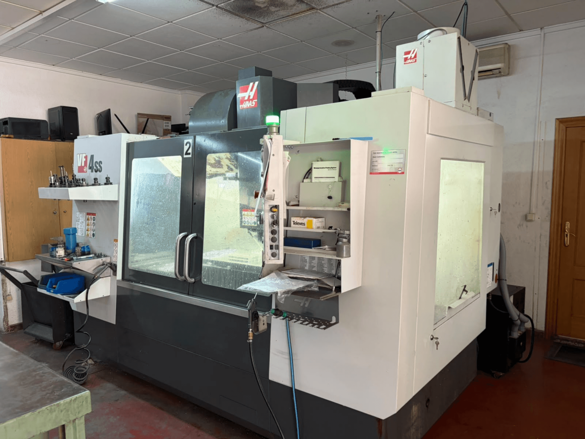 HAAS VF 4SS vertical machining center in a workshop, front view, showing control panel and work area with tools and materials.
