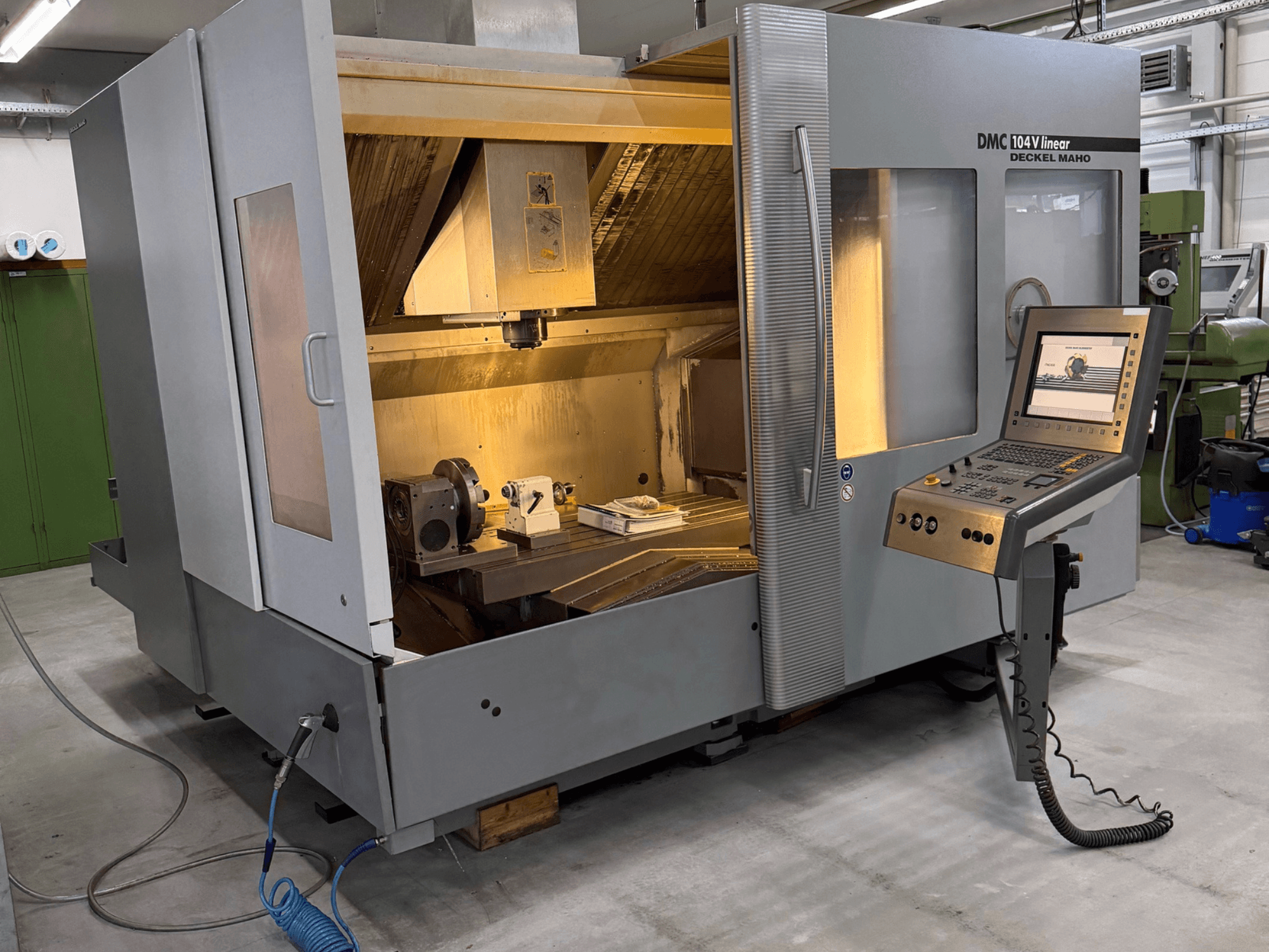 DMC 104 V linear vertical machining center in a workshop, showcasing the control panel and partially open enclosure.