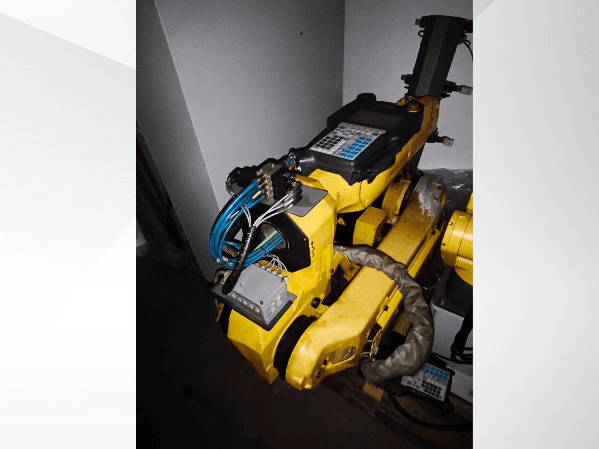 FANUC M-20iA robot arm in a side view, showcasing yellow body, control panel, and connected wiring.