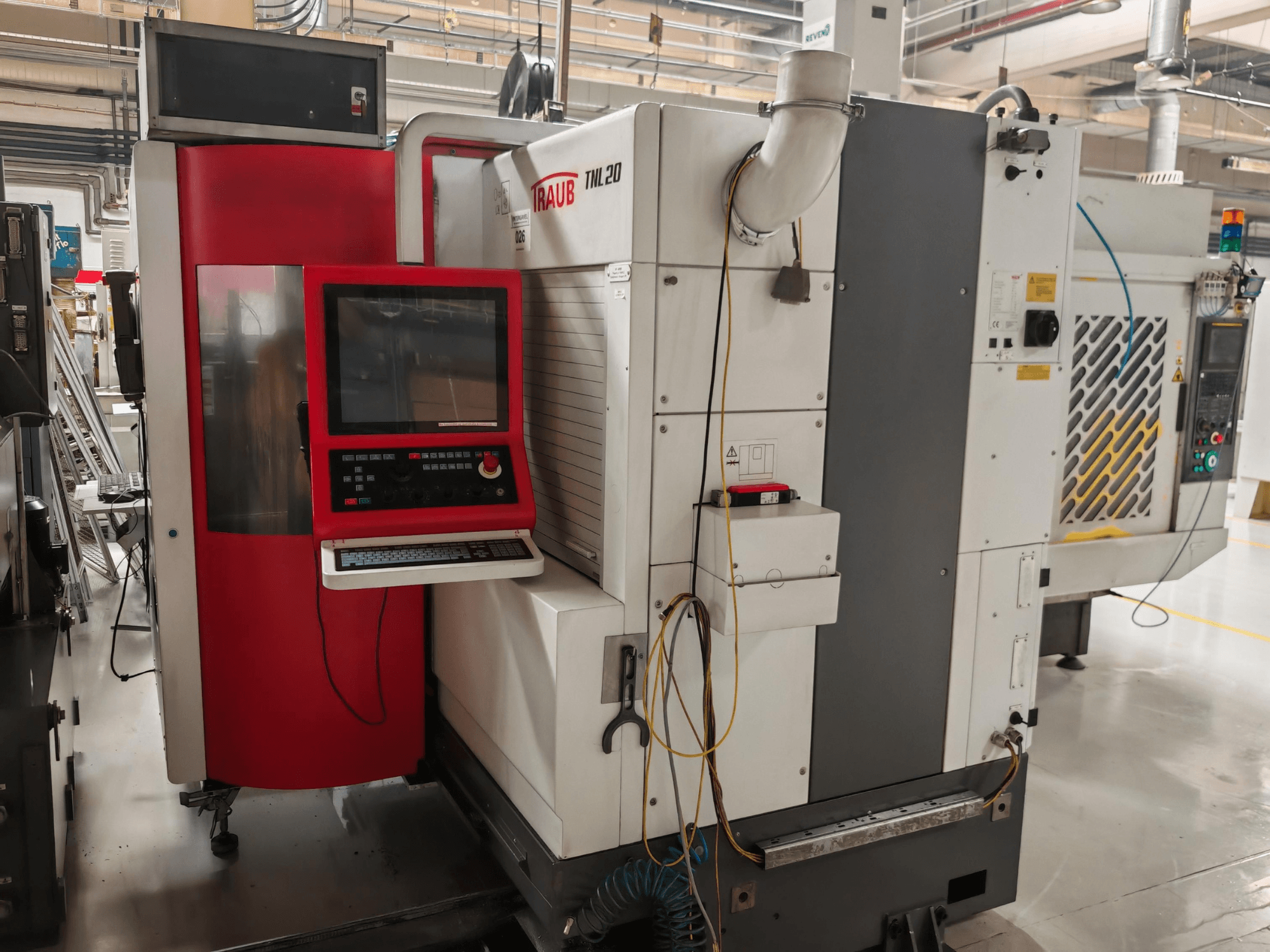 TRAUB TLN20 Swiss type turning machine, front view showing control panel, red enclosure, and industrial details.