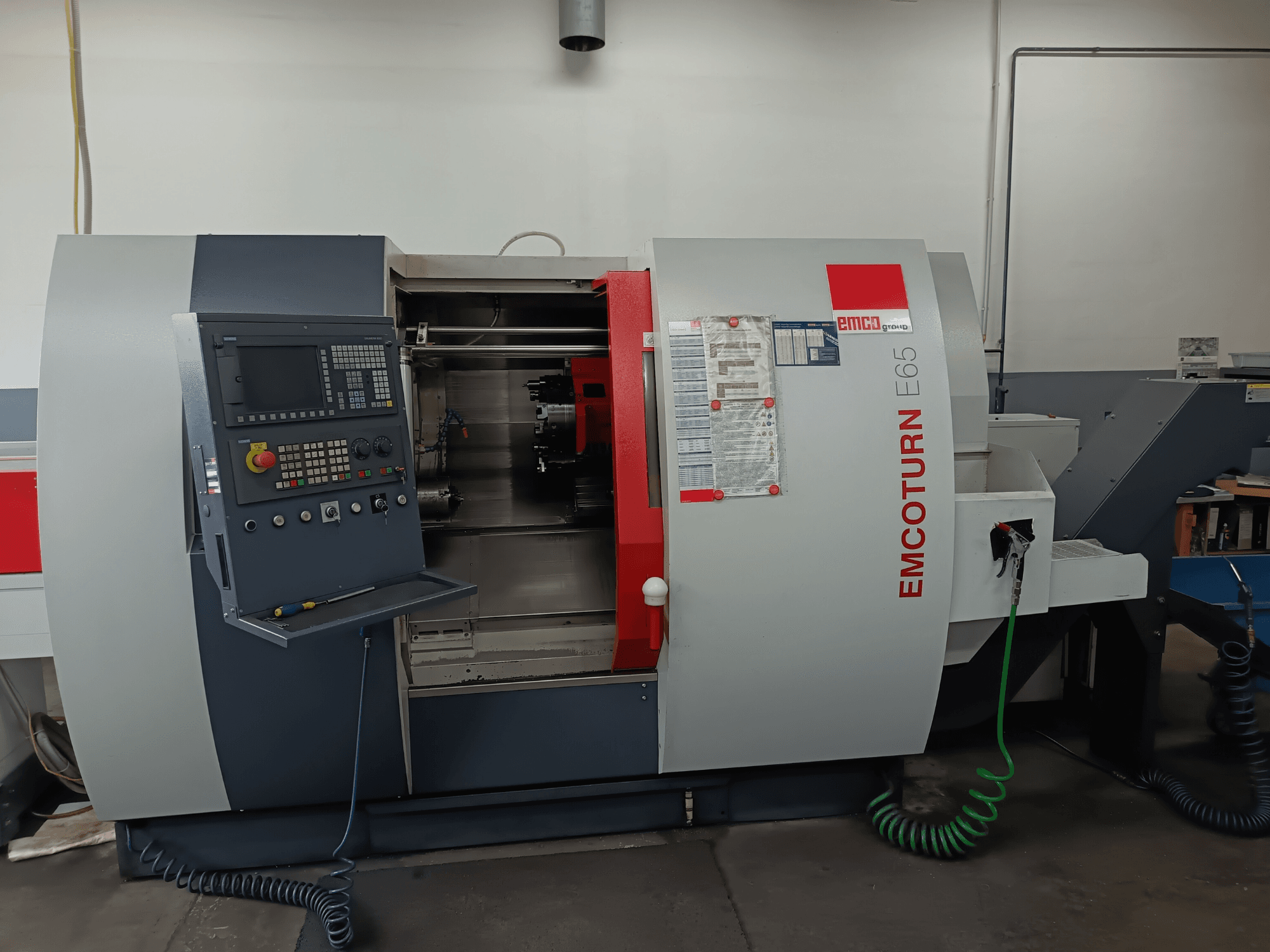 EMCO EMCOTURN E65 turn-mill centre, front view showing control panel, internal mechanism, and features in a workshop setting.