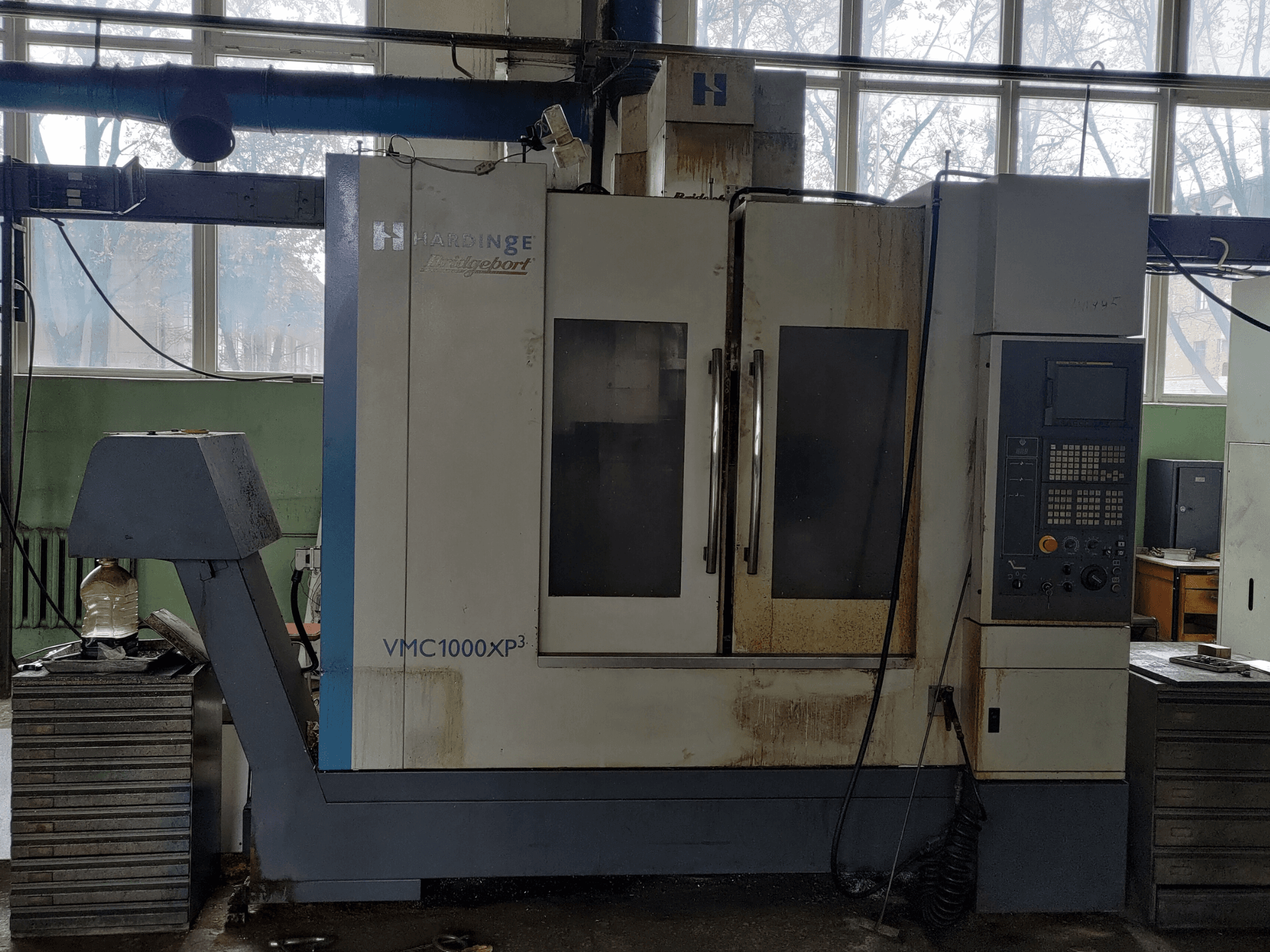 Bridgeport VMC1000 XP3 vertical machining center in front view, showing control panel and slight wear.