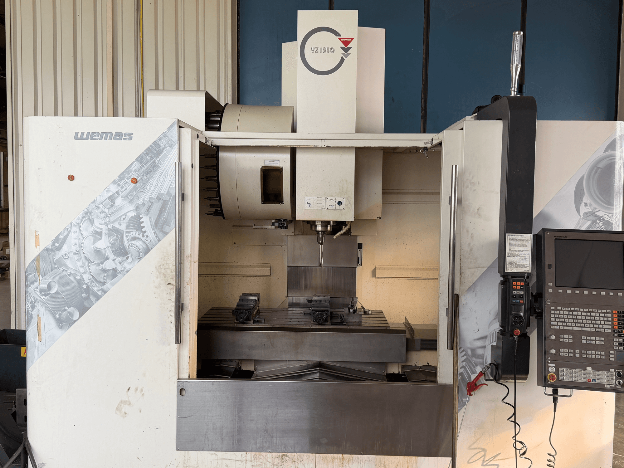 WEMAS VZ 1250 vertical machining center, front view, showing control panel, spindle, and workpiece hold-downs on a bed.