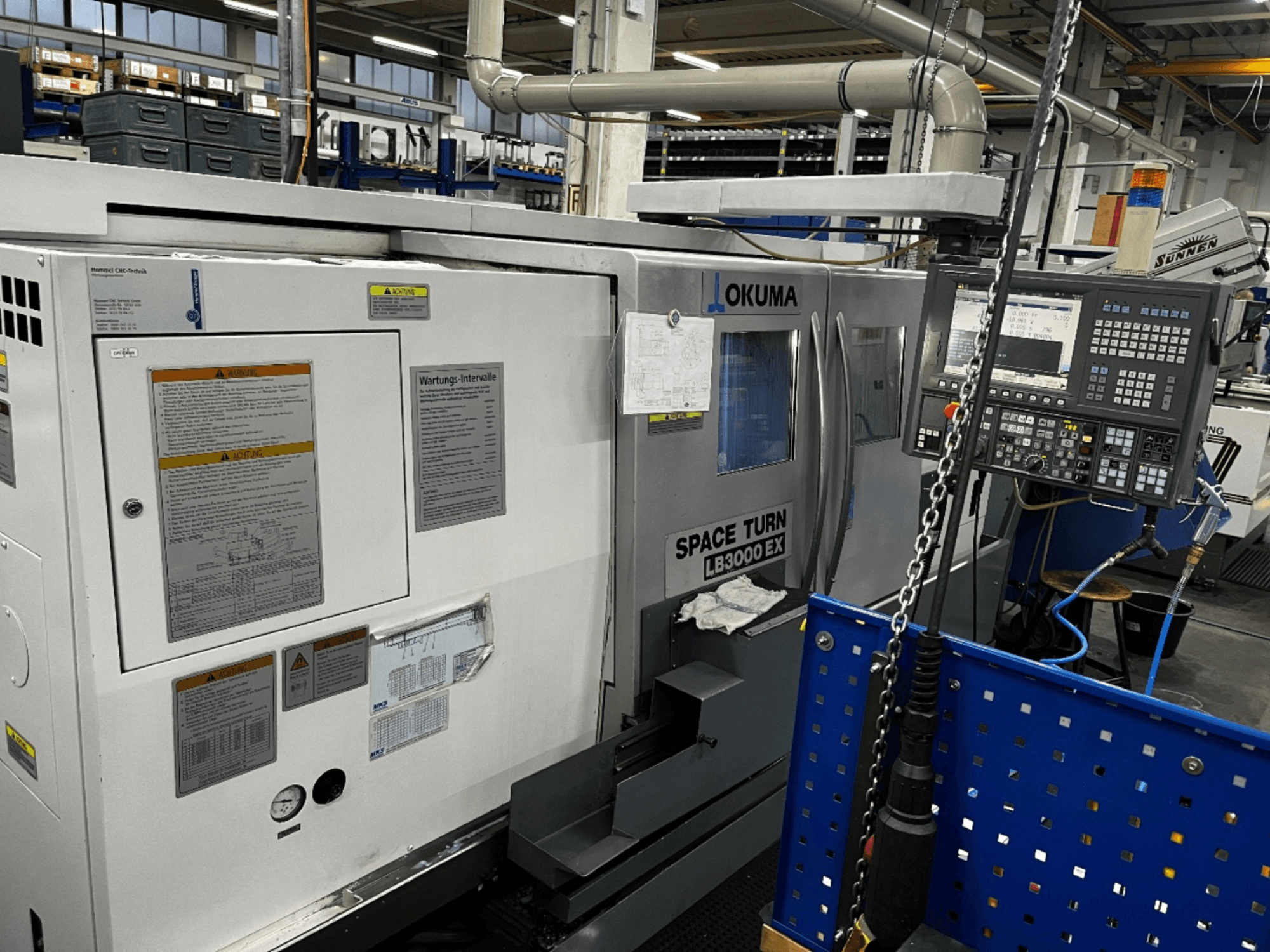 Okuma LB3000 EX horizontal turning machine, front view, displaying control panel and safety information on the side.