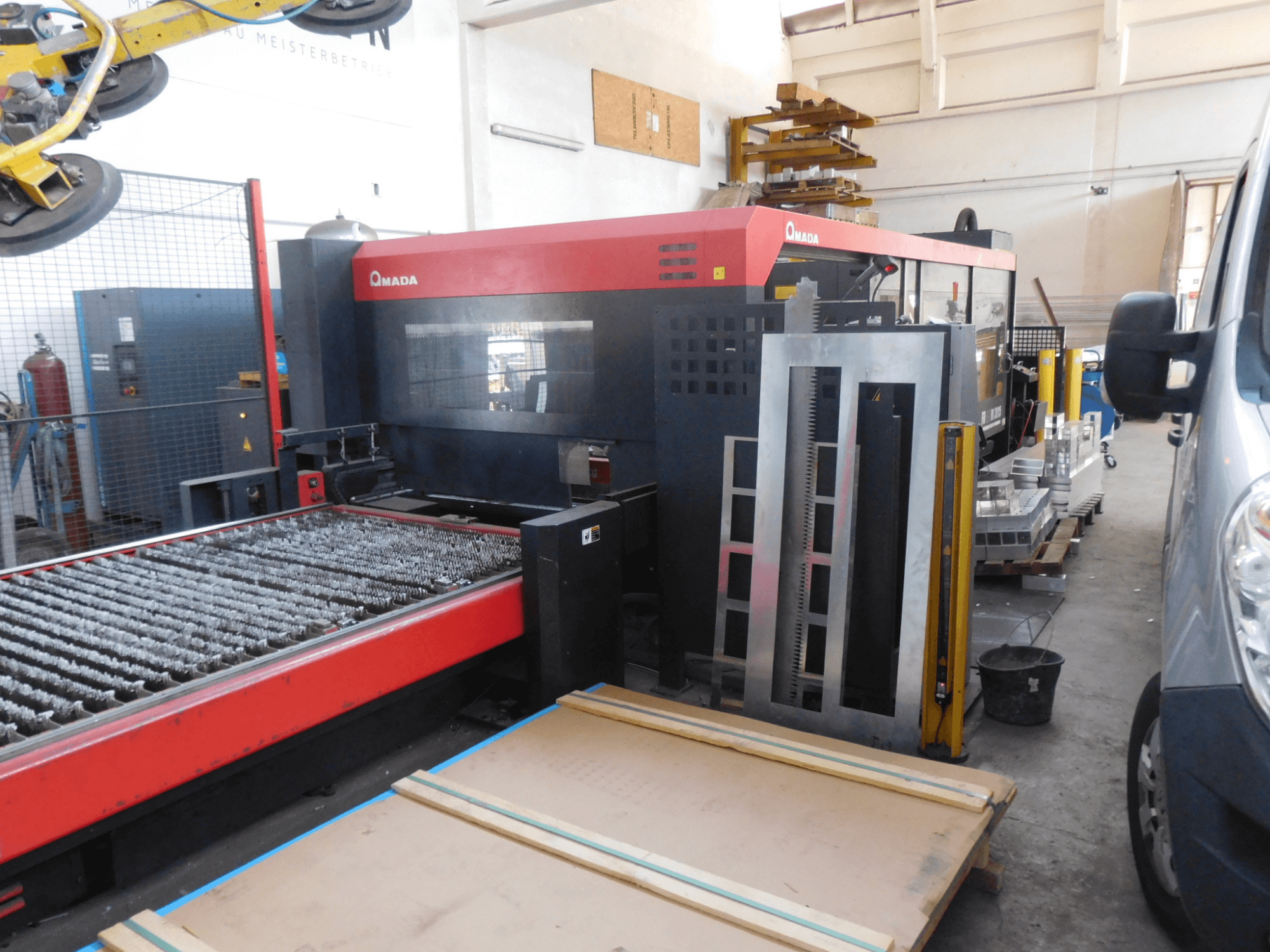 Front view of AMADA FO-3015 II RI CO2 laser cutting machine, featuring a cutting bed and surrounding work area.