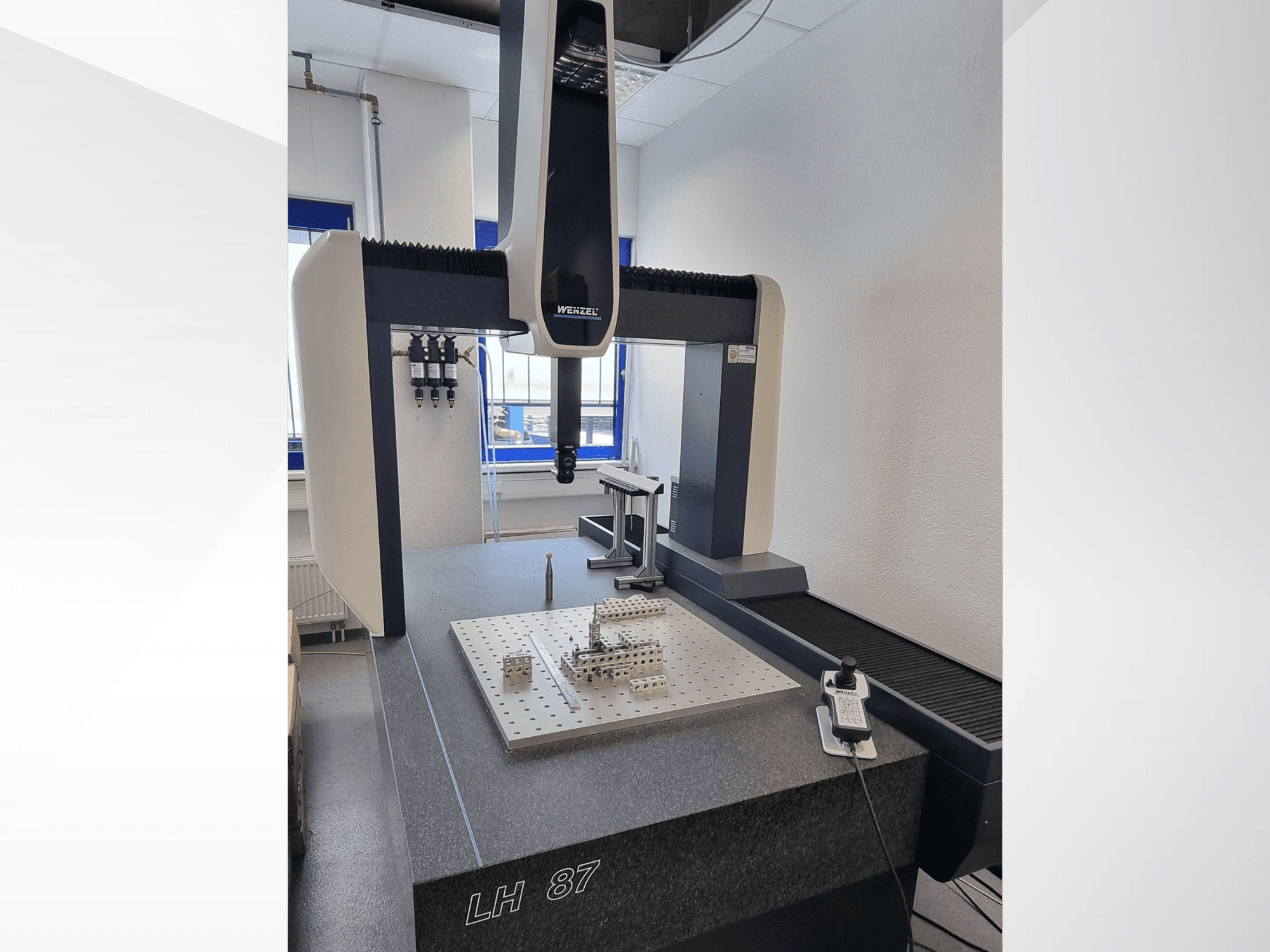 Wenzel LH 87 CMM in a lab, front view with measurement probe over a precision surface plate and digital controller visible.