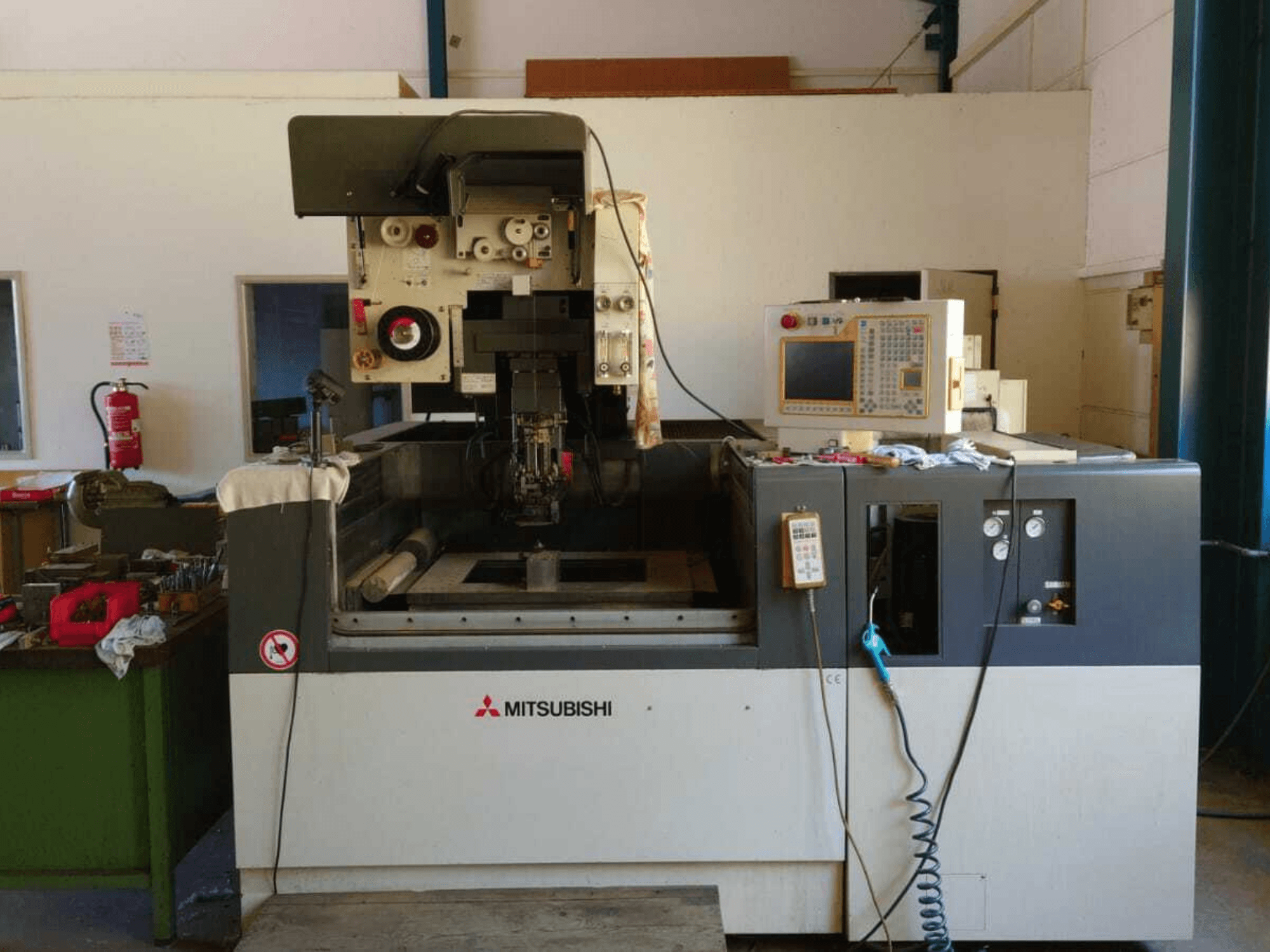 Mitsubishi FA20 Wire EDM Machine front view with control panel, work area, and safety signage visible.