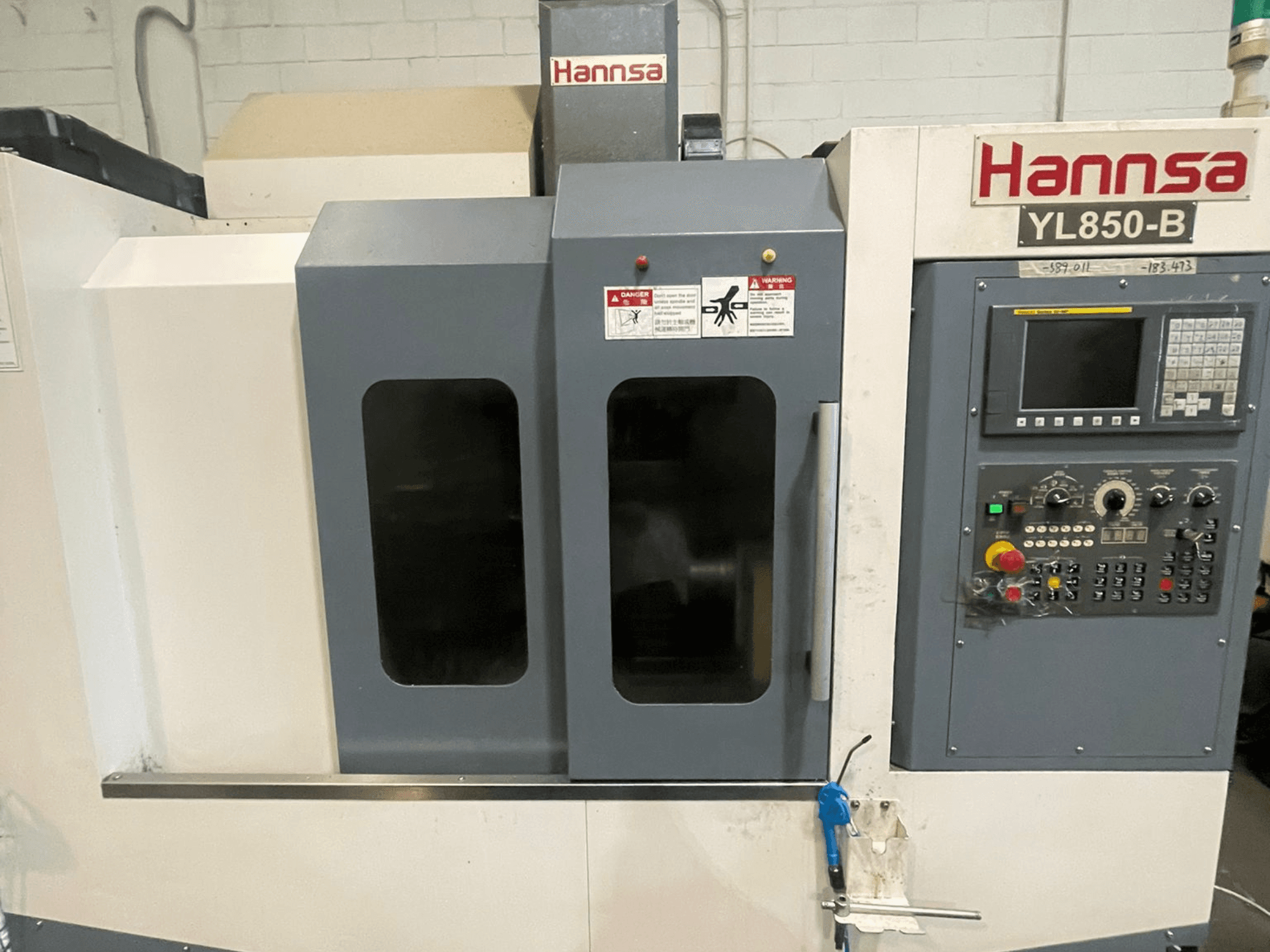 Vertical machining center HANNSA YL850-B, front view, featuring control panel, operation buttons, and dual observation windows.