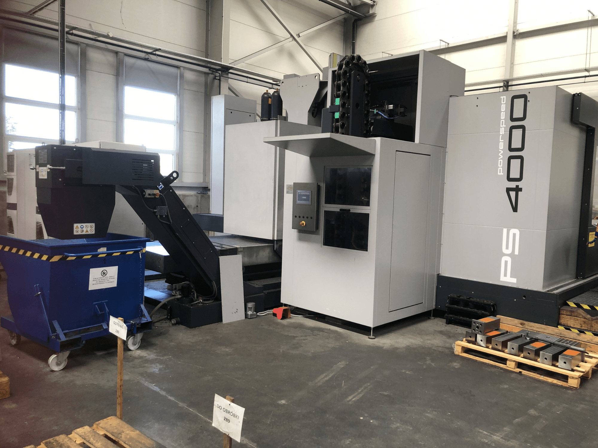 Horizontal machining centre SHW PowerSpeed 4000 in a factory setting, showcasing control panel, conveyor, and workpieces.