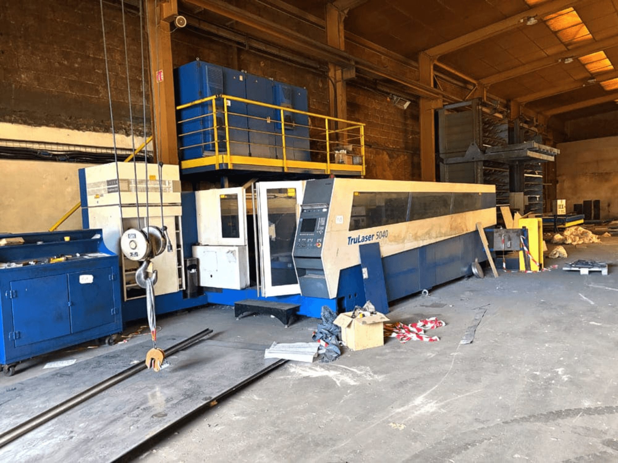 CO2 laser cutting machine from TRUMPF, model TRULASER 5040, shown in a workshop, angled front view with a cluttered background.