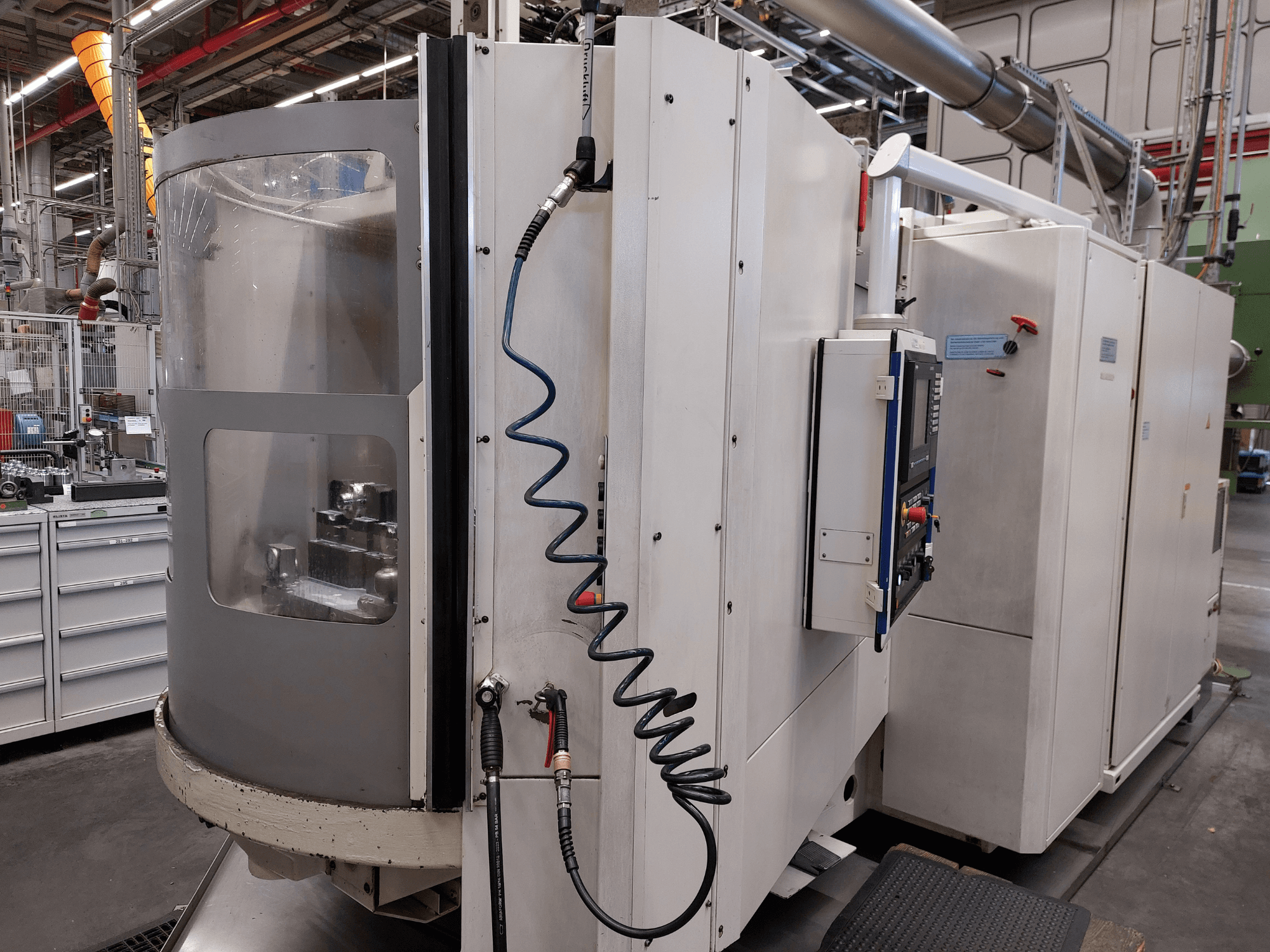 Heller MC 16 horizontal machining center in side view, showcasing control panel, air hose, and transparent window view of the workspace.