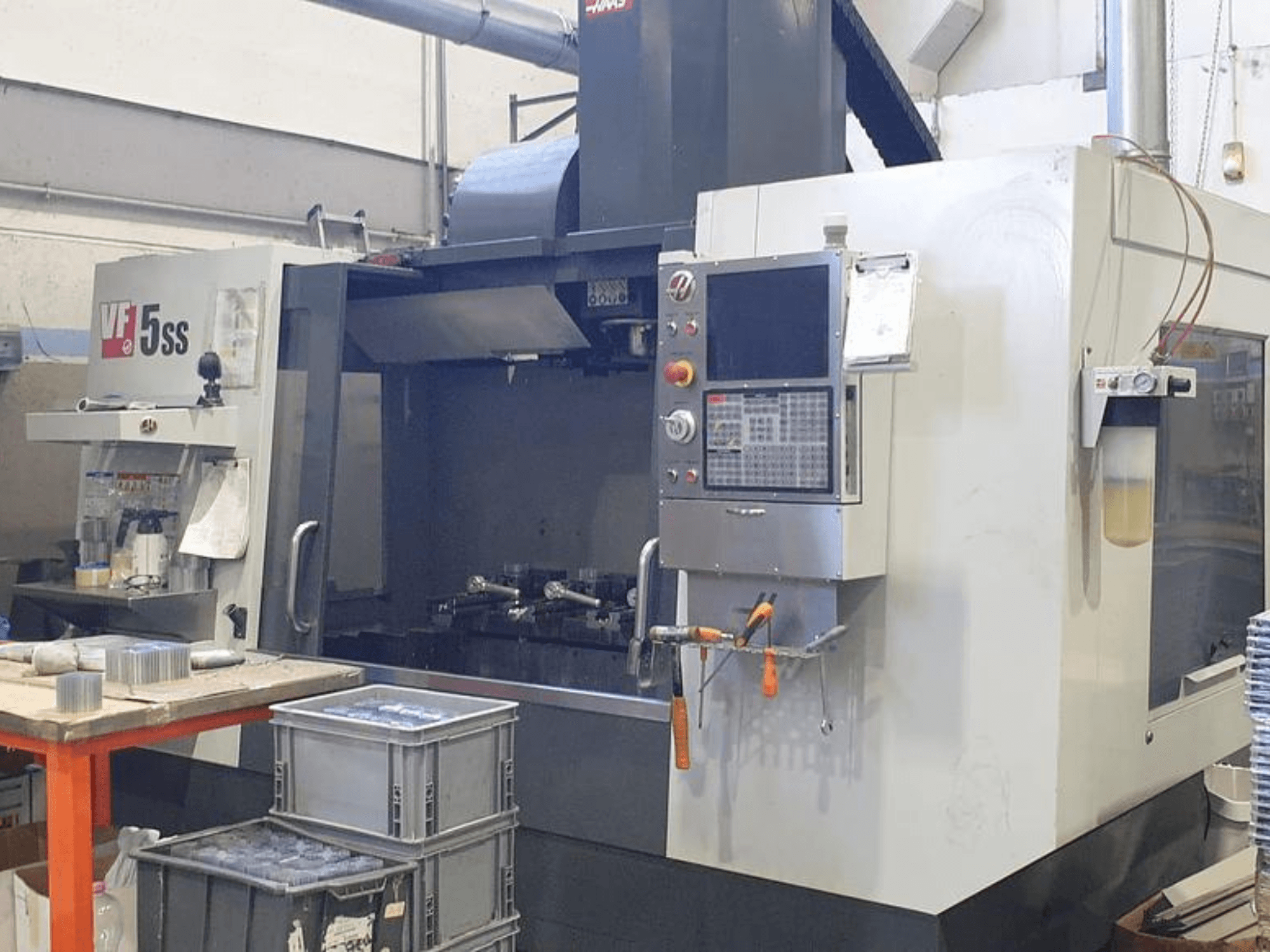 HAAS VF-5SS vertical machining center in front view, showing control panel, workspace, and storage bins.