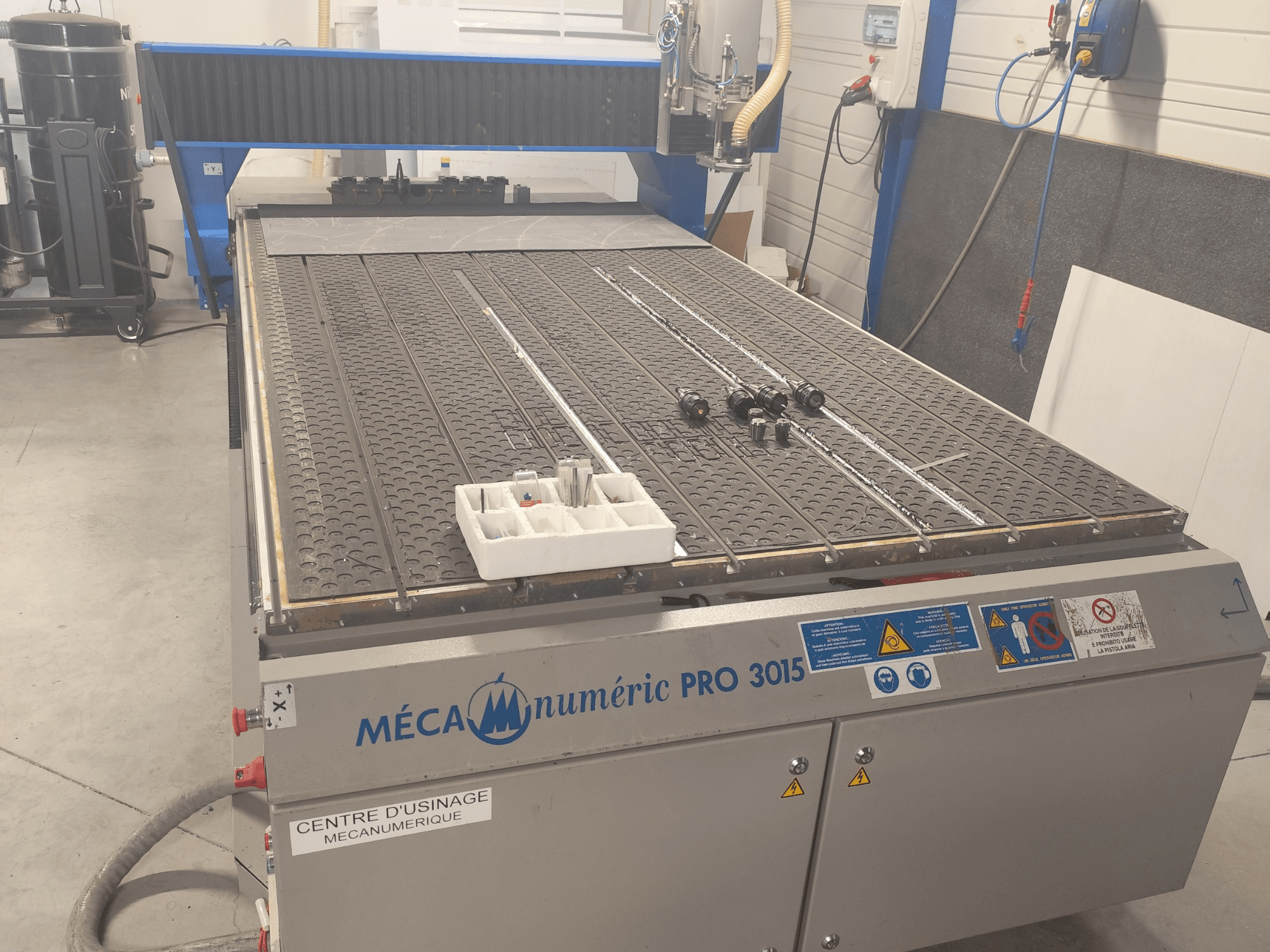 CNC Router MECANUMERIC Pro 3015 front view, featuring a detailed cutting bed, control panel, and accessories on the table.