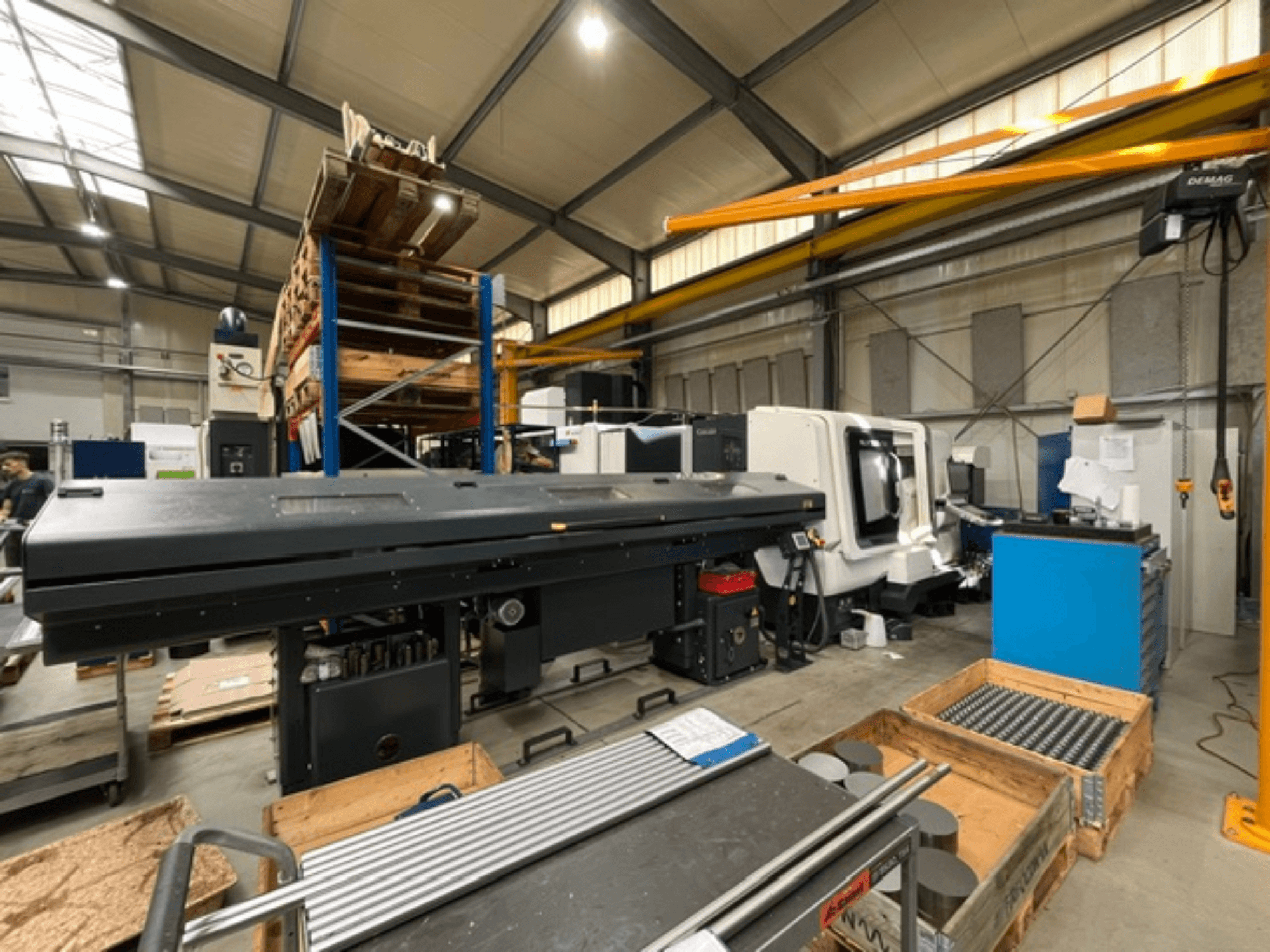 DMG MORI MORI NLX 2500/700 SY horizontal turning machine in a factory setting, viewed from the side, with tools and pallets visible.