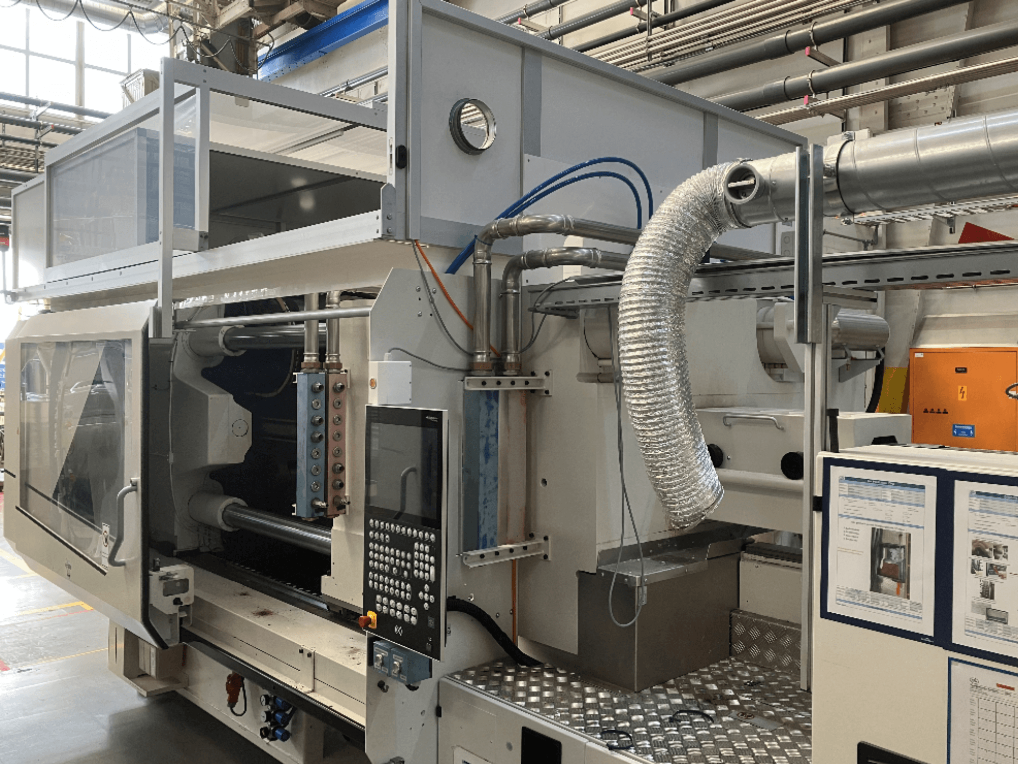 Industrial machine from Brand X, side view showing control panel, ductwork, and machinery components in a factory setting.