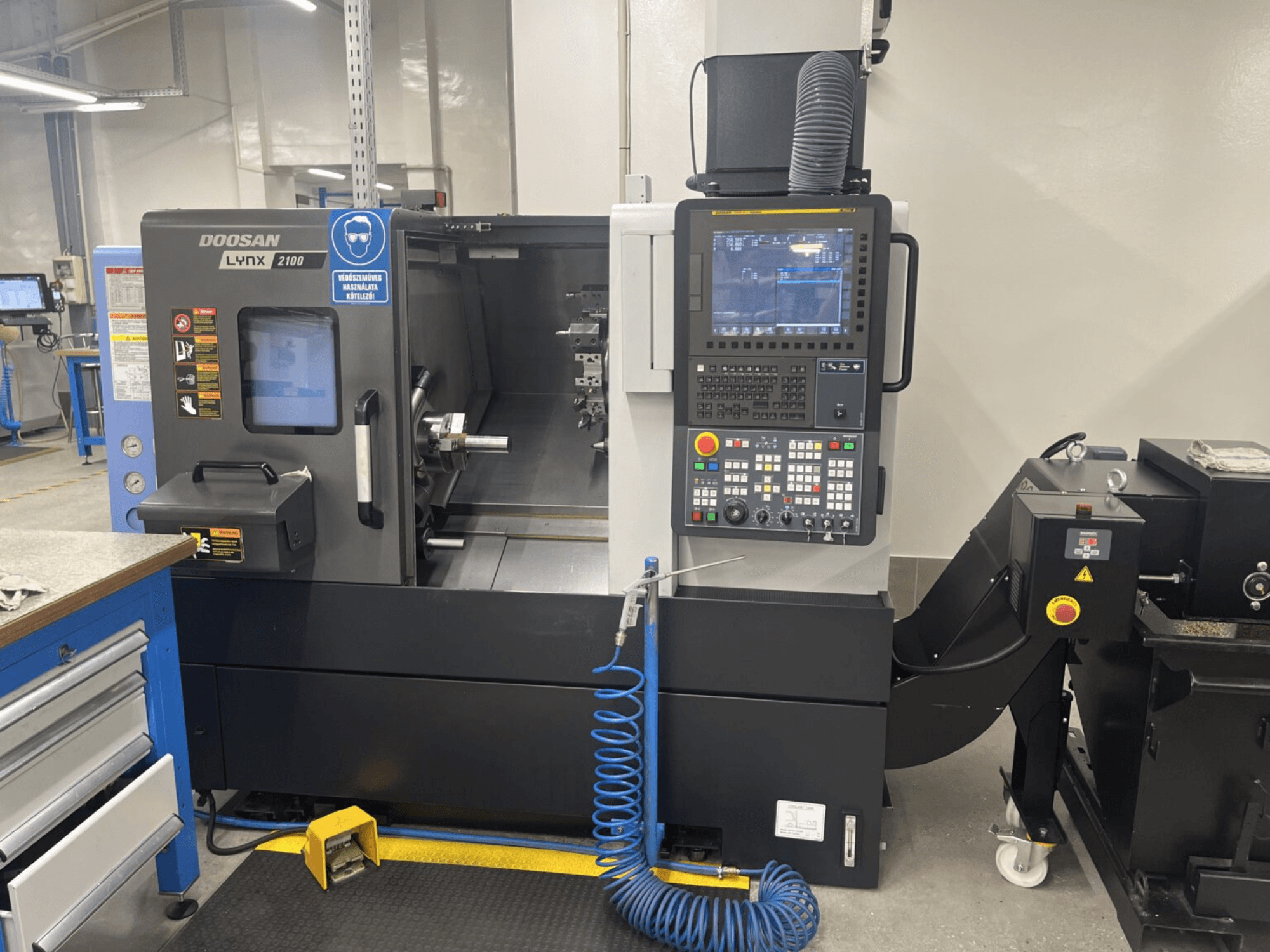 Front view of a DOOSAN Lynx 2100A horizontal turning machine, showcasing control panel and spindle area with notable safety features.