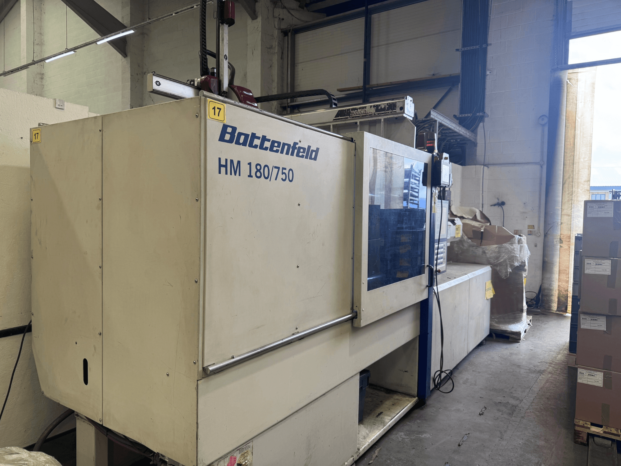 Battenfeld HM150750 hydraulic injection moulding machine viewed from the front, showcasing its control panel and surrounding setup.