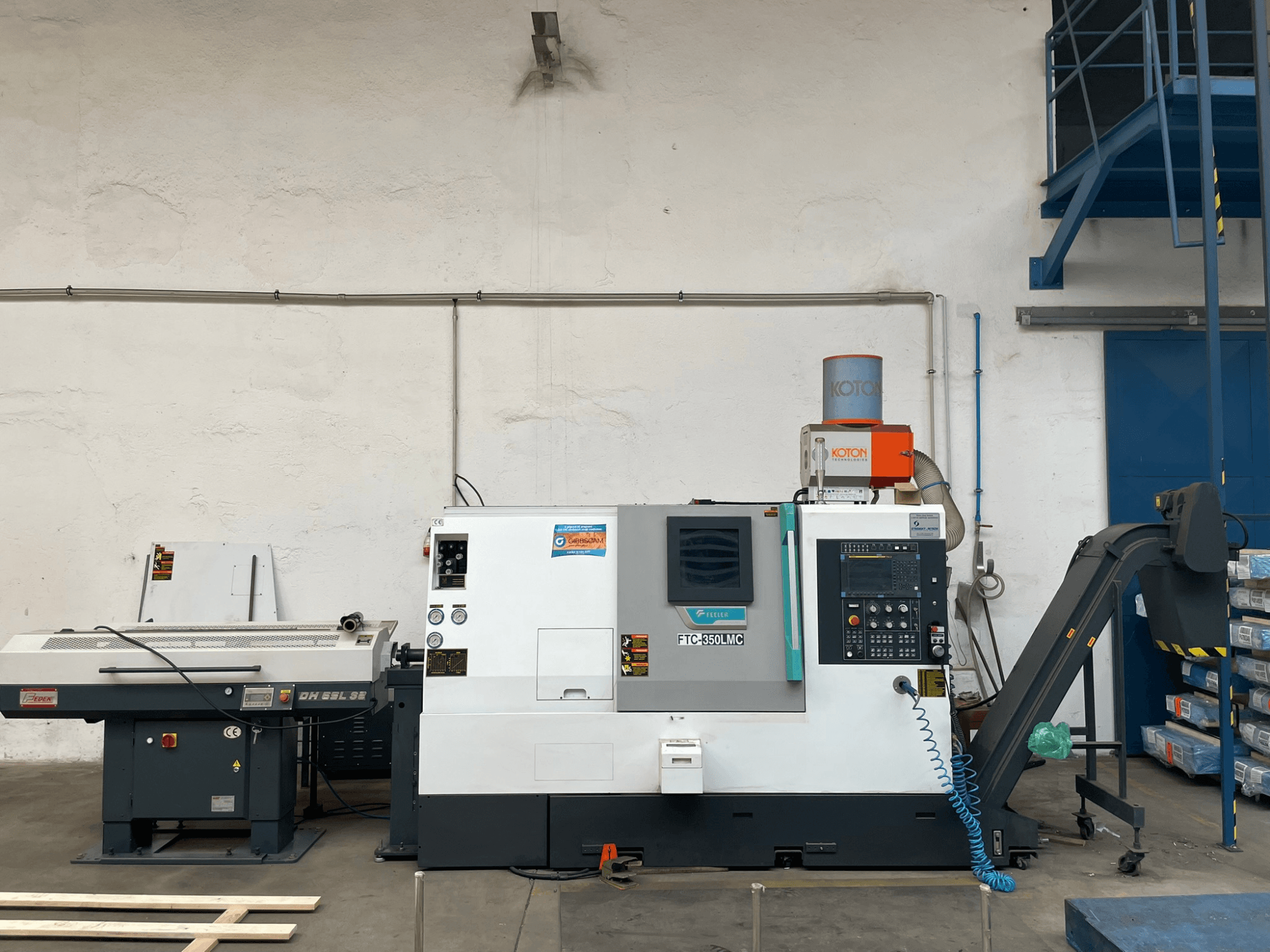 Feeler FTC 350 LMC horizontal turning machine in a workshop, showcasing control panel and tool feed lines. Side view.