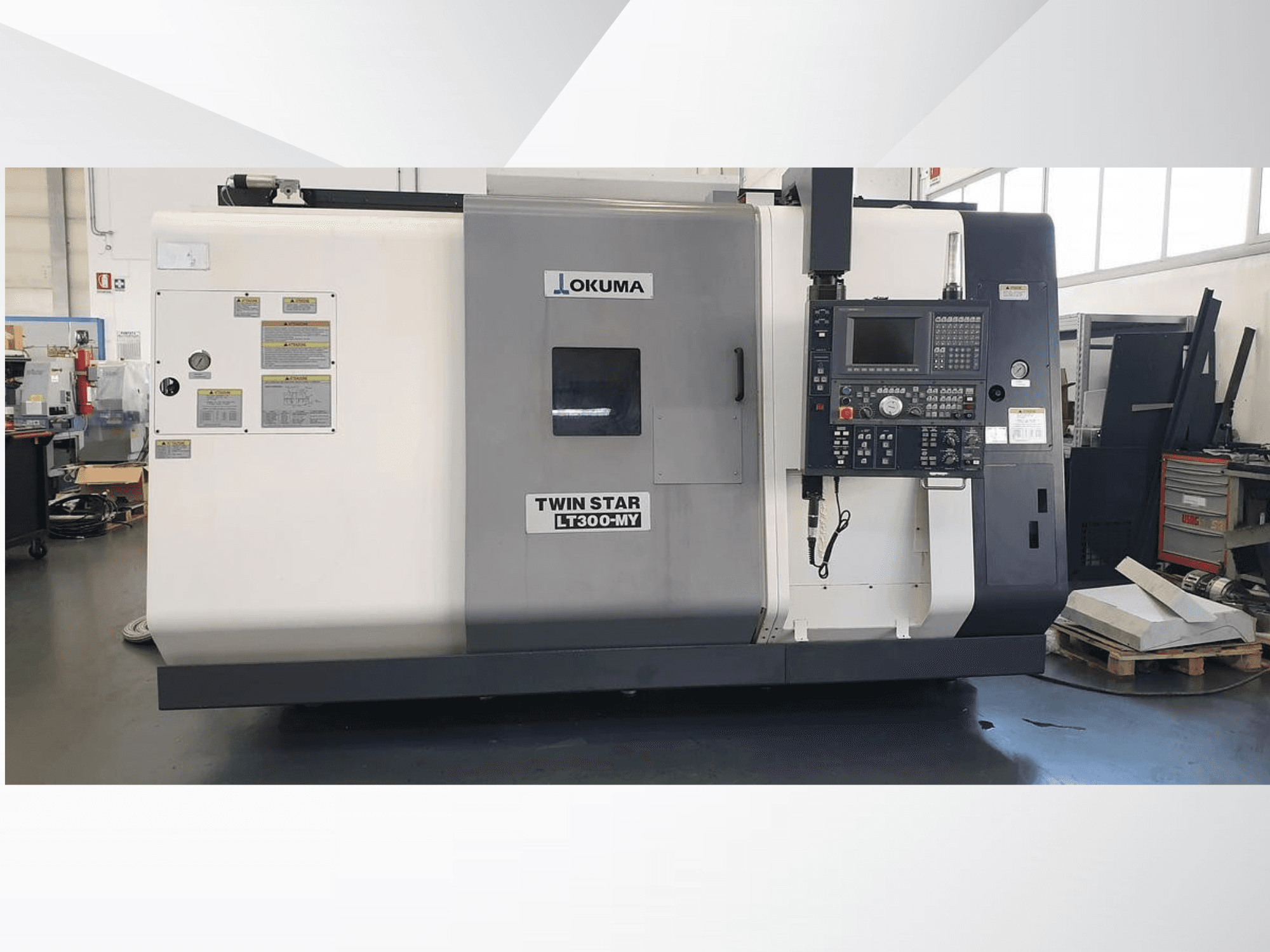 Okuma Twin Star LT300-MY CNC lathe machine, front view with control panel and operational labels visible.