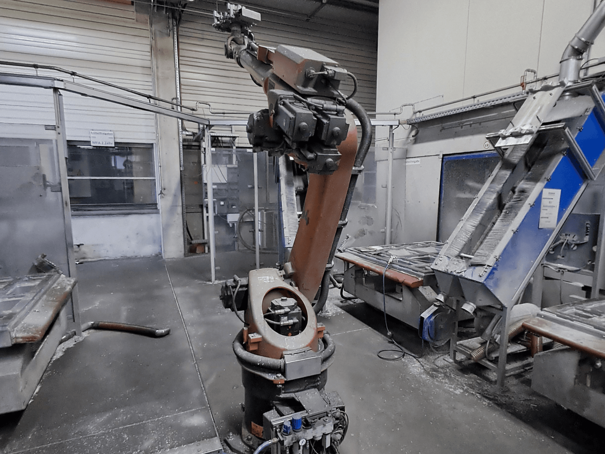 KUKA KR 30L16-2 robot arm in a workshop setting, front view, with visible dust and machinery in the background.