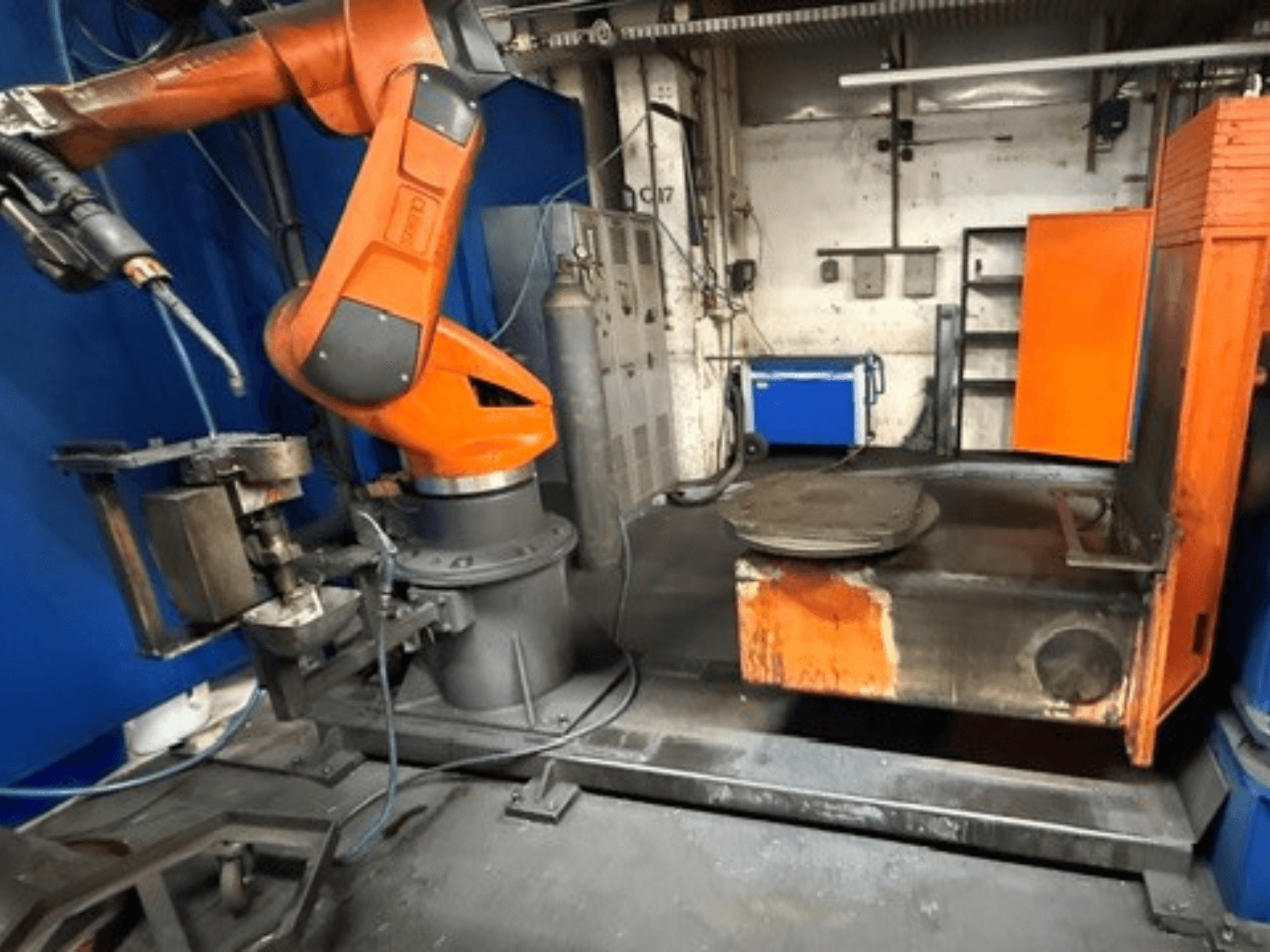 CLOOS C50 welding robot in a front view, featuring an orange robotic arm and a metal work table.