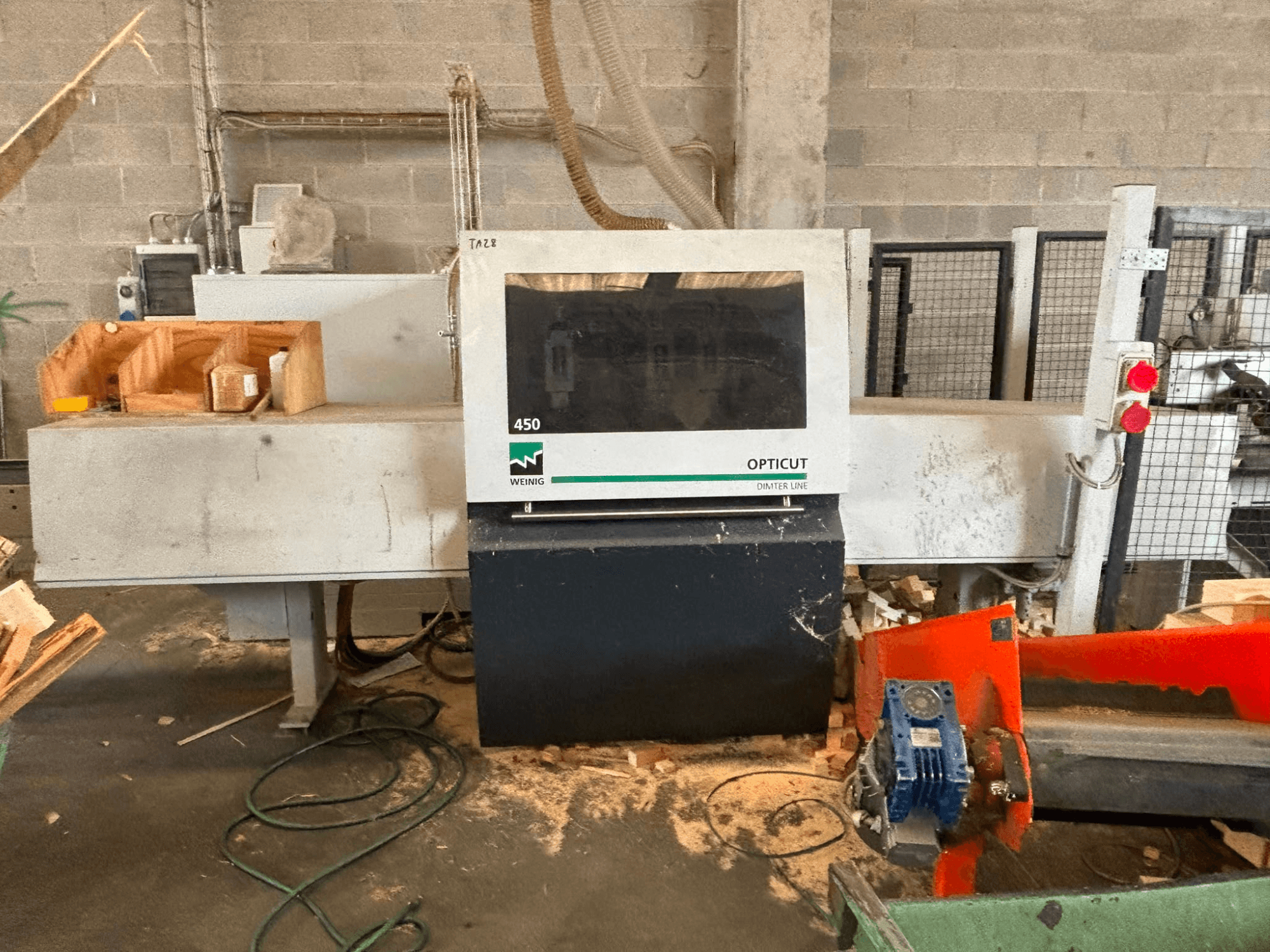 WEINIG OptiCut 450 optimizing cross-cut saw, front view, showing control panel, cutting area, and wood pieces on the table.