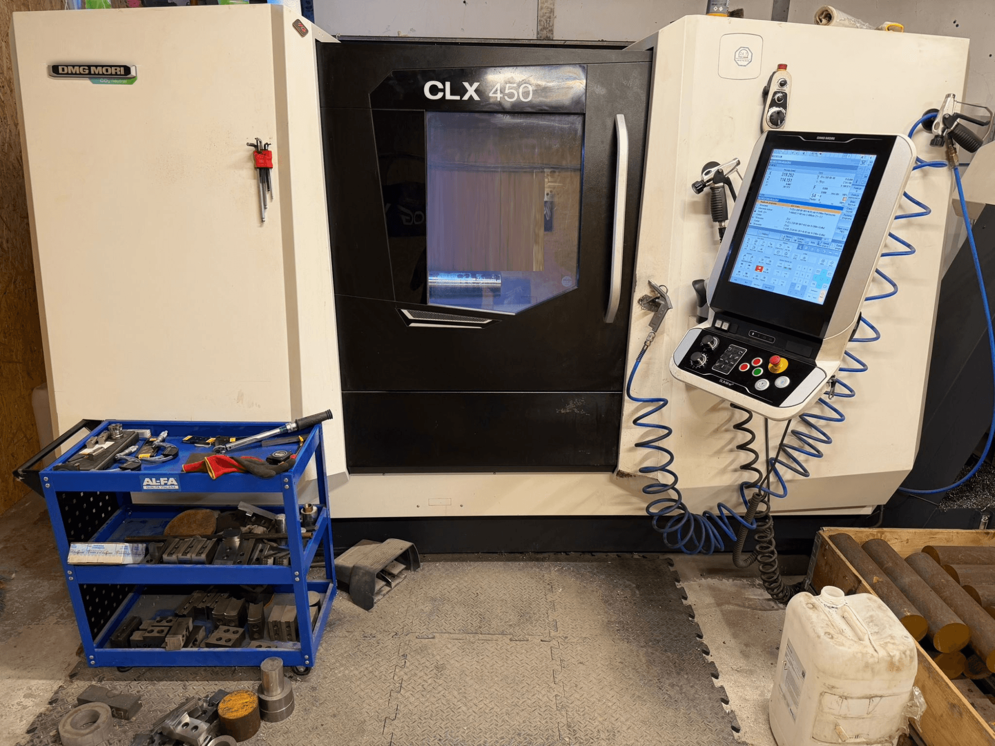 DMG MORI CLX 450 V3 horizontal turning machine front view, featuring a control panel and nearby tool cart with equipment.