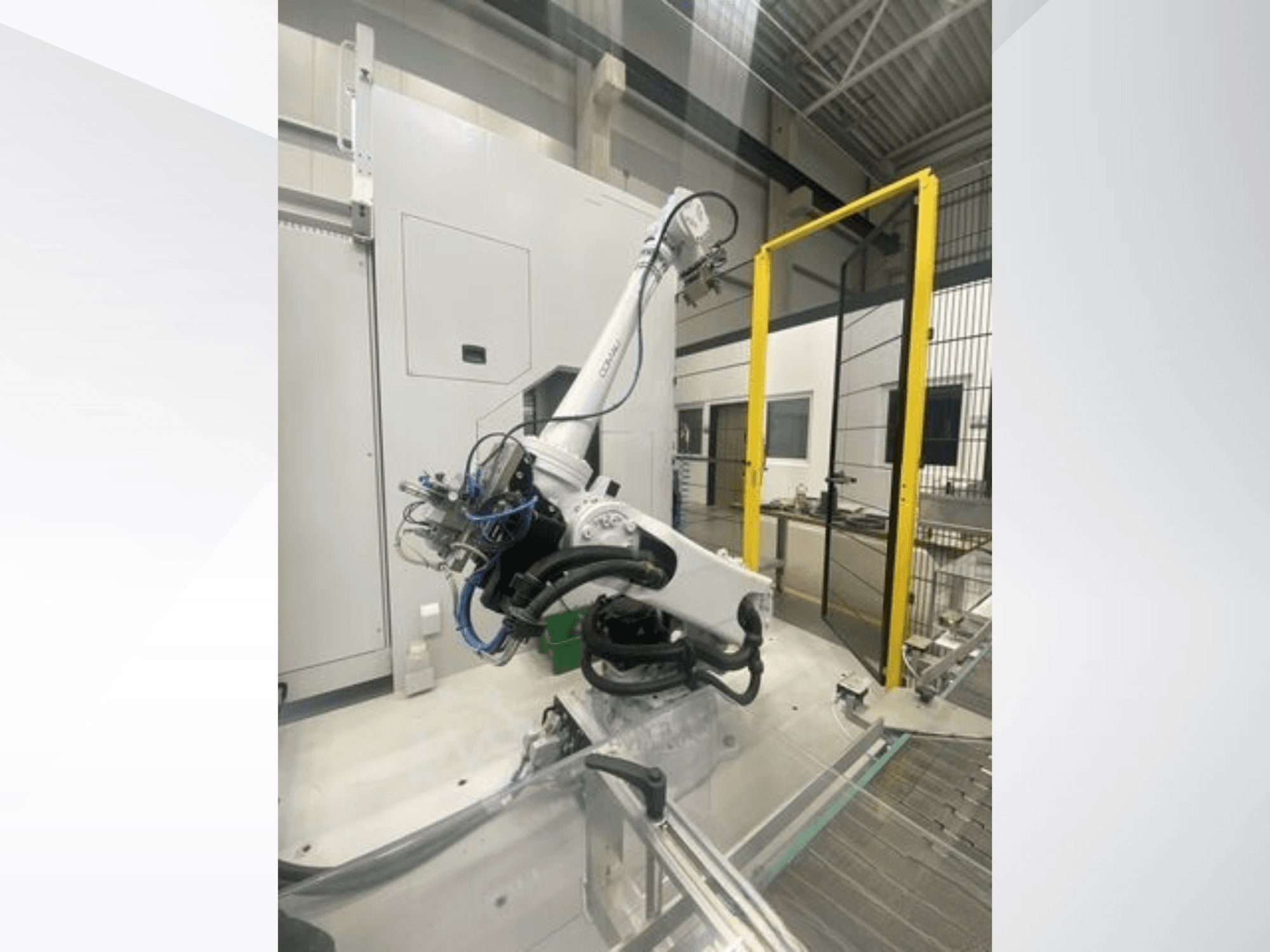 COMAU Smart NJ 40-2.5 robot arm in side view, featuring cables and a yellow safety gate in a factory setting.