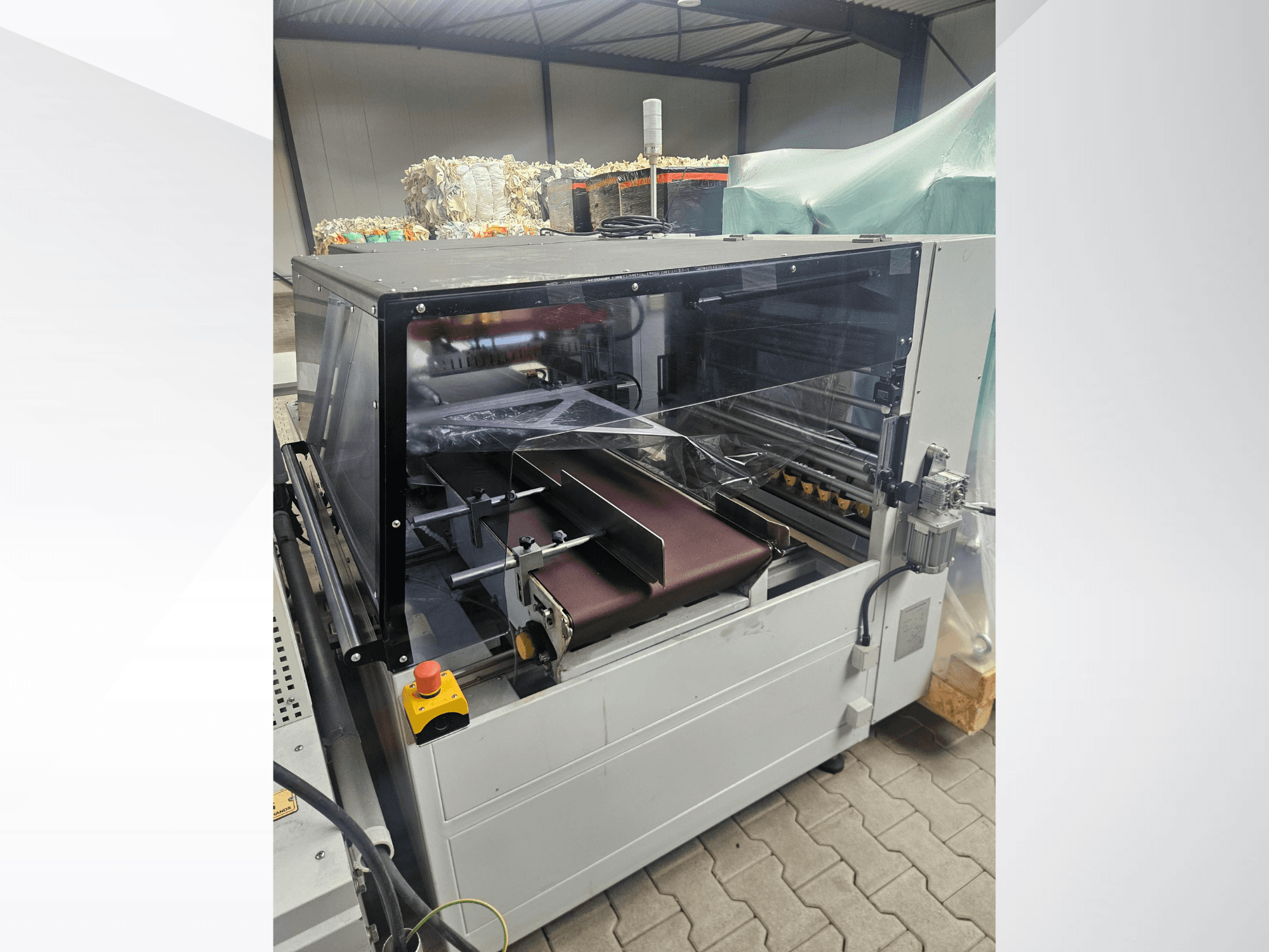 AMTEC Speed Shrink 40 PRO machine, front view, showcasing a plastic processing mechanism with a clear safety cover and conveyor belt.