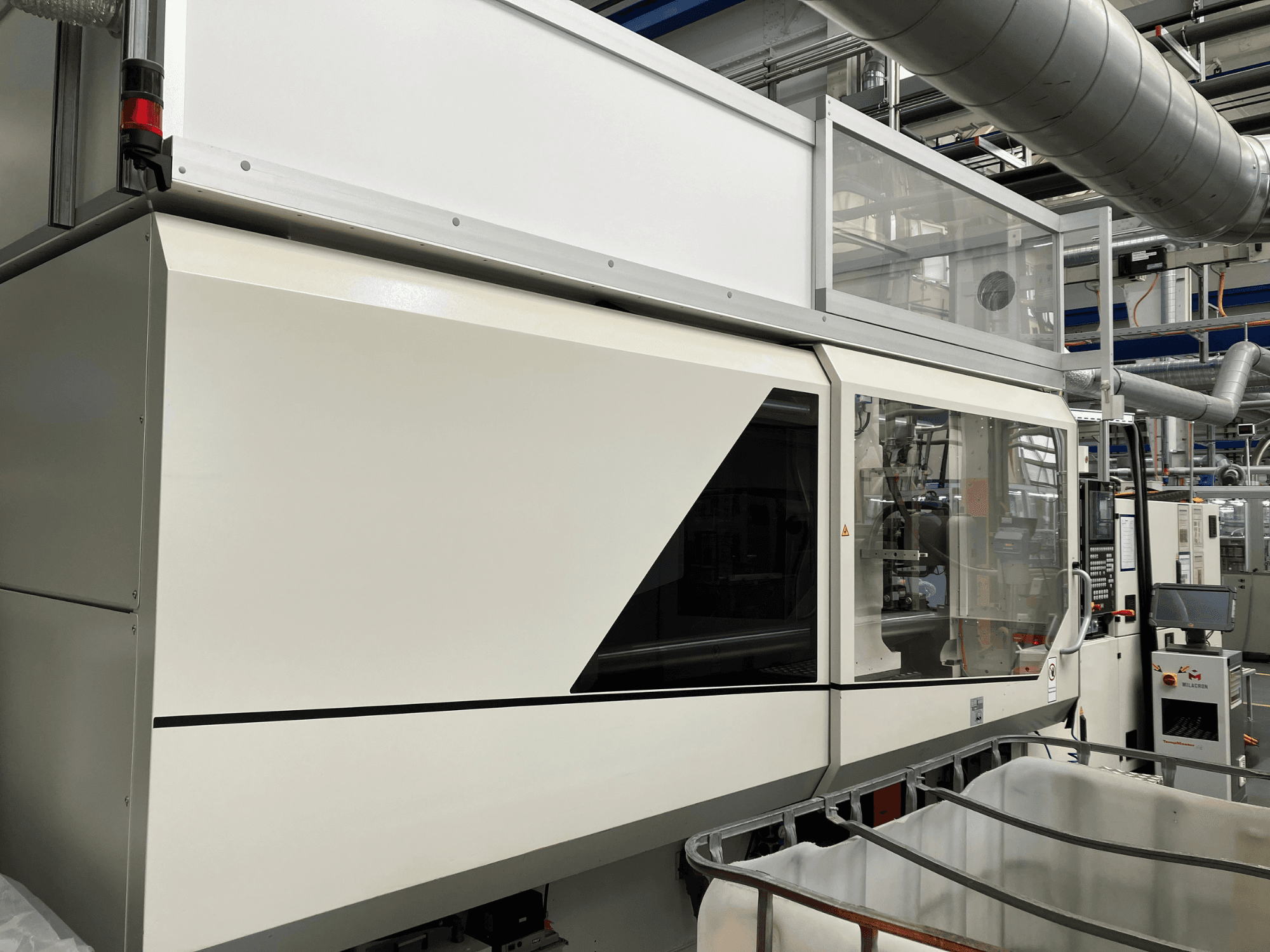 Industrial machine front view, featuring a sleek white design, display panel, and glass section for visibility of components.