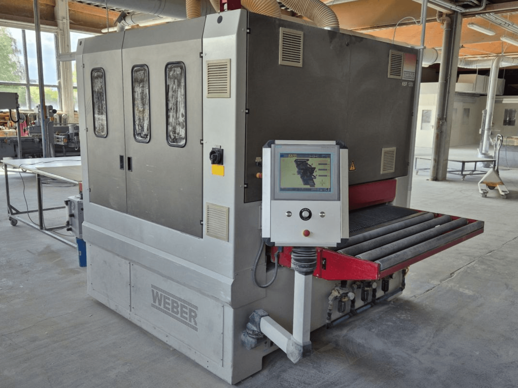 WEBER KSF-3-1350 belt sander, side view showing controls, power panel, and sanding conveyor. Industrial setting with machines visible.